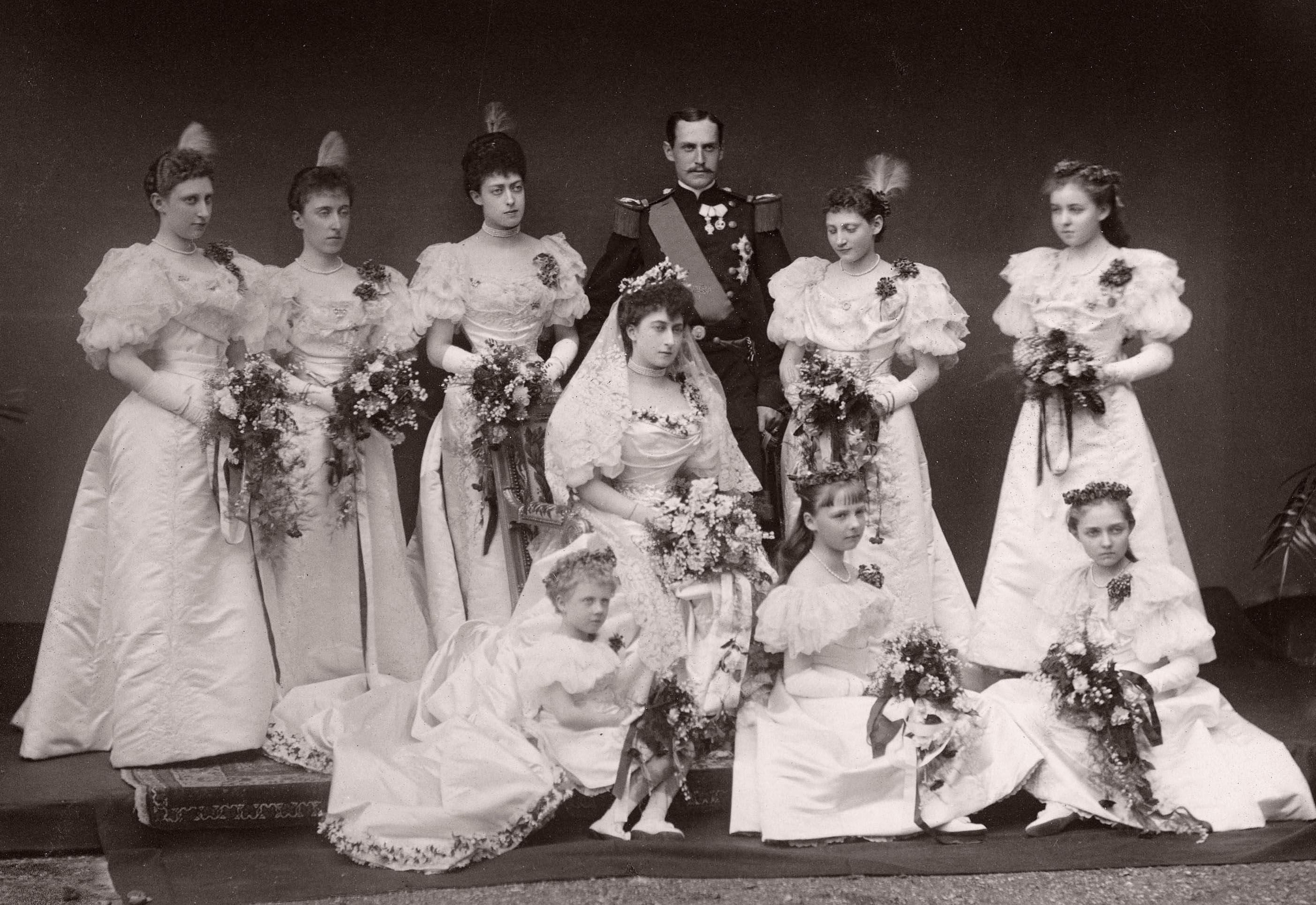 Brudeparet i gallauniform og brudekjole omgitt av åtte brudepiker.