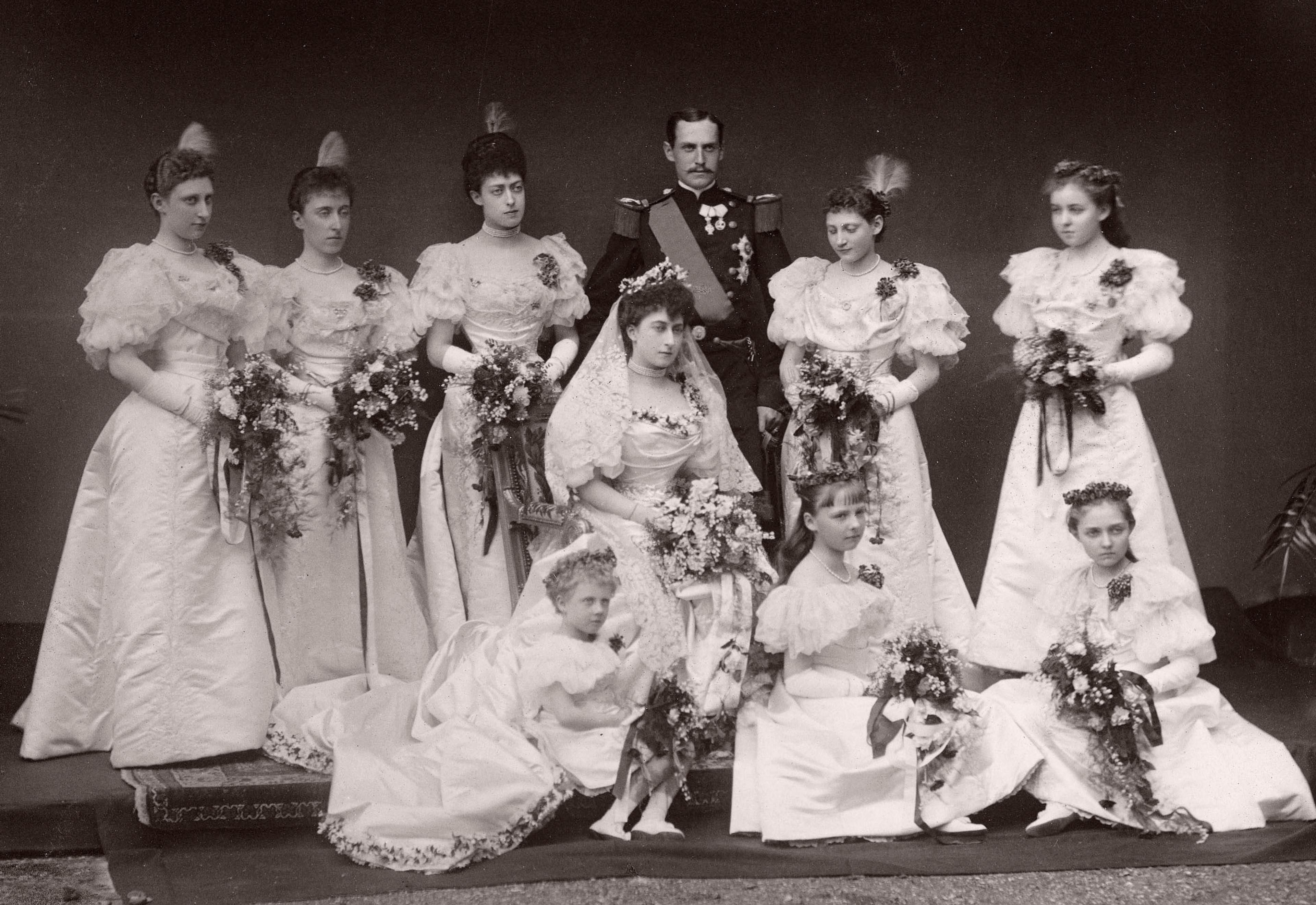 Brudeparet i gallauniform og brudekjole omgitt av åtte brudepiker.