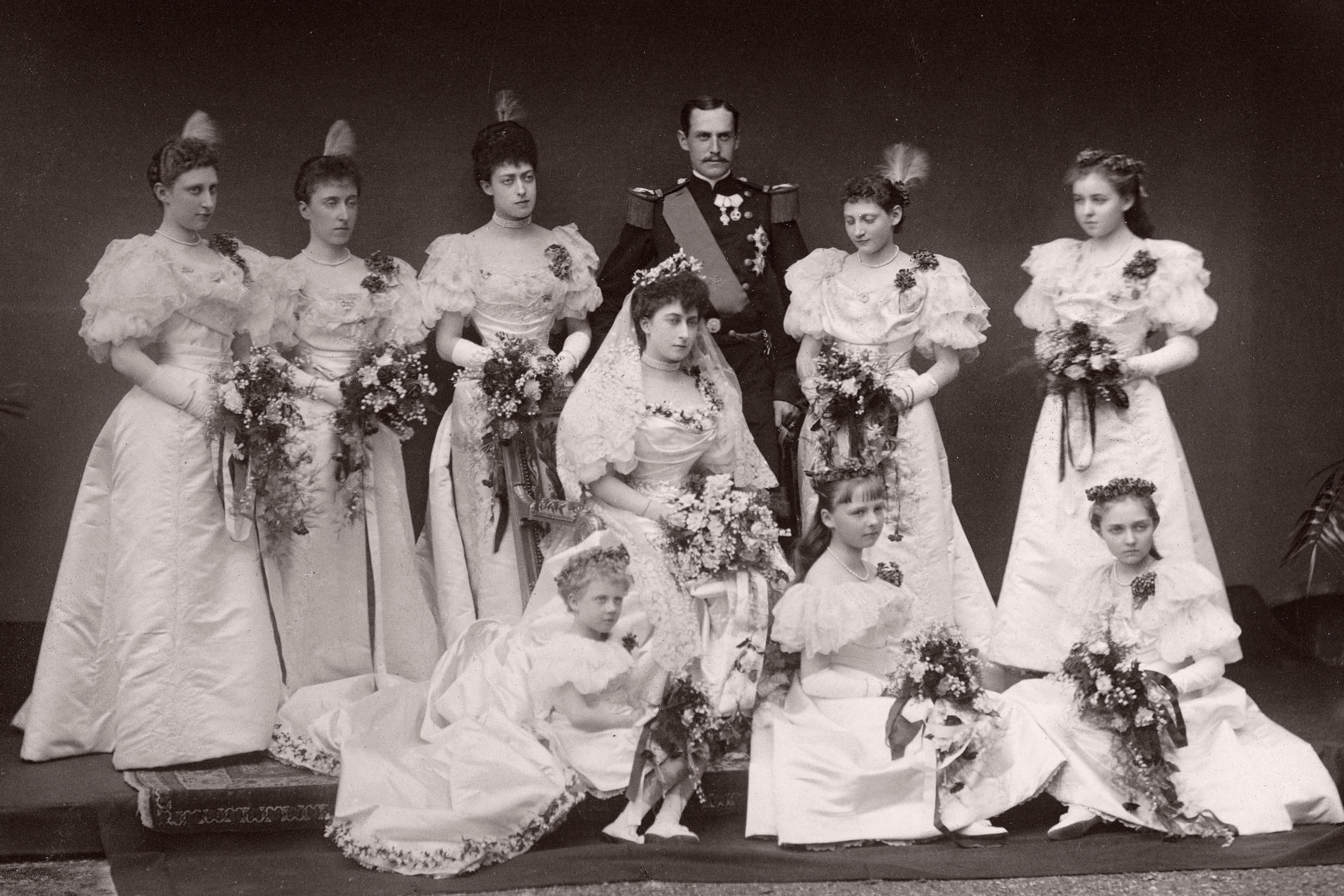 Brudeparet i gallauniform og brudekjole omgitt av åtte brudepiker.