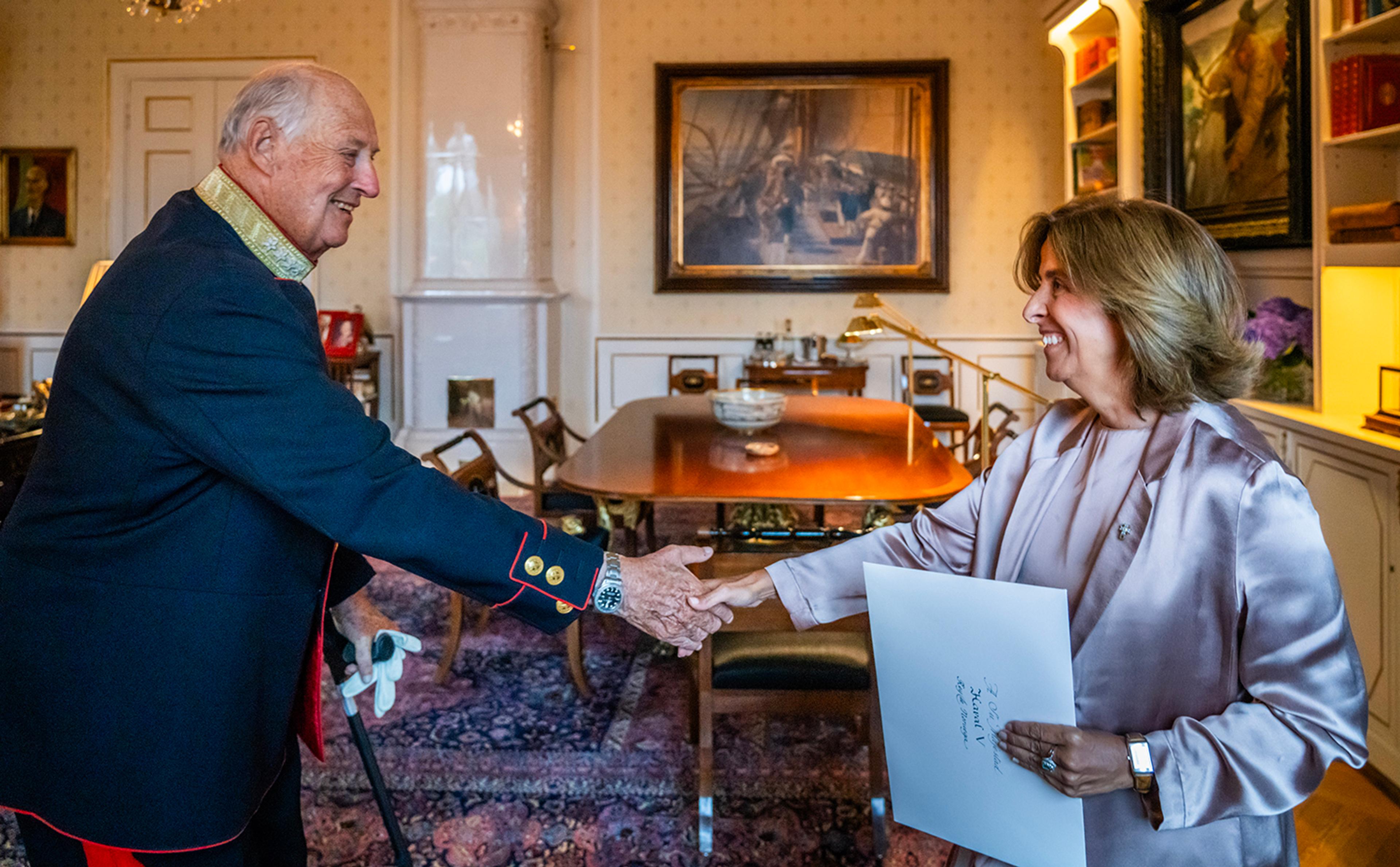 Kongen og ambassadøren håndhilser smilende på hverandre på Kongens kontor.
