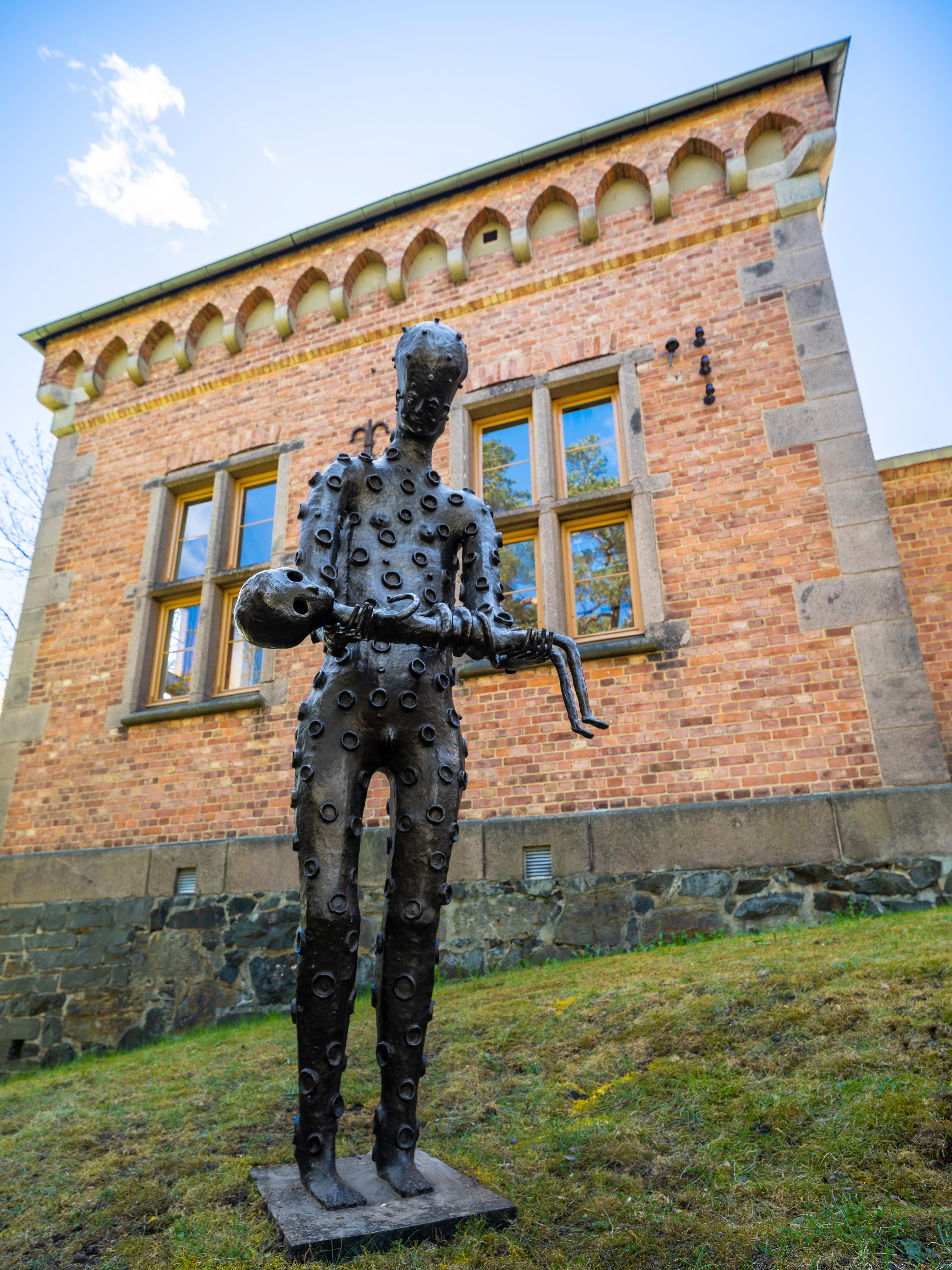 Mørk skulptur av en skikkelse med et lite barn i armene.