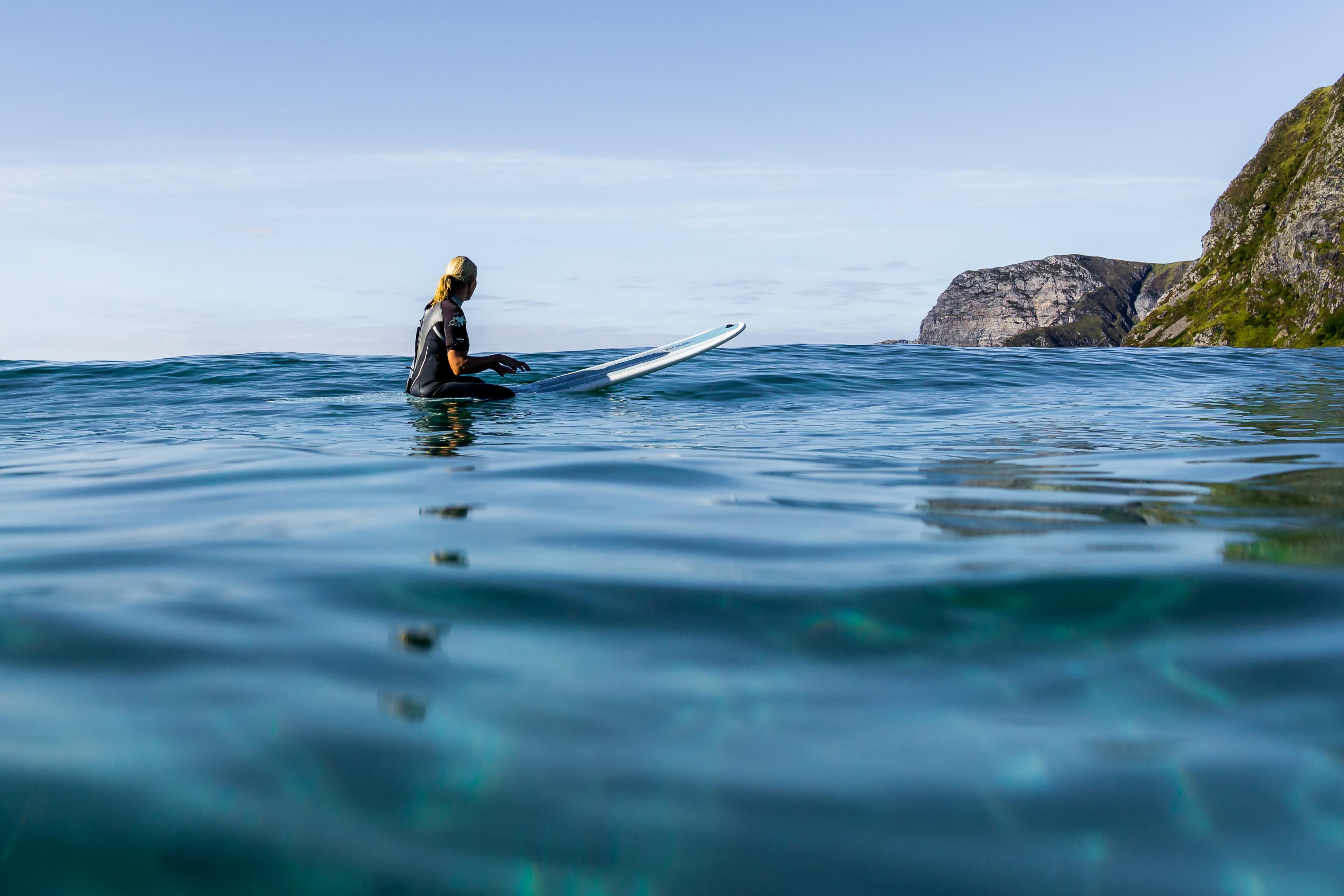 Kronprinsessen sitter på surfebrettet på fjorden og ser utover.