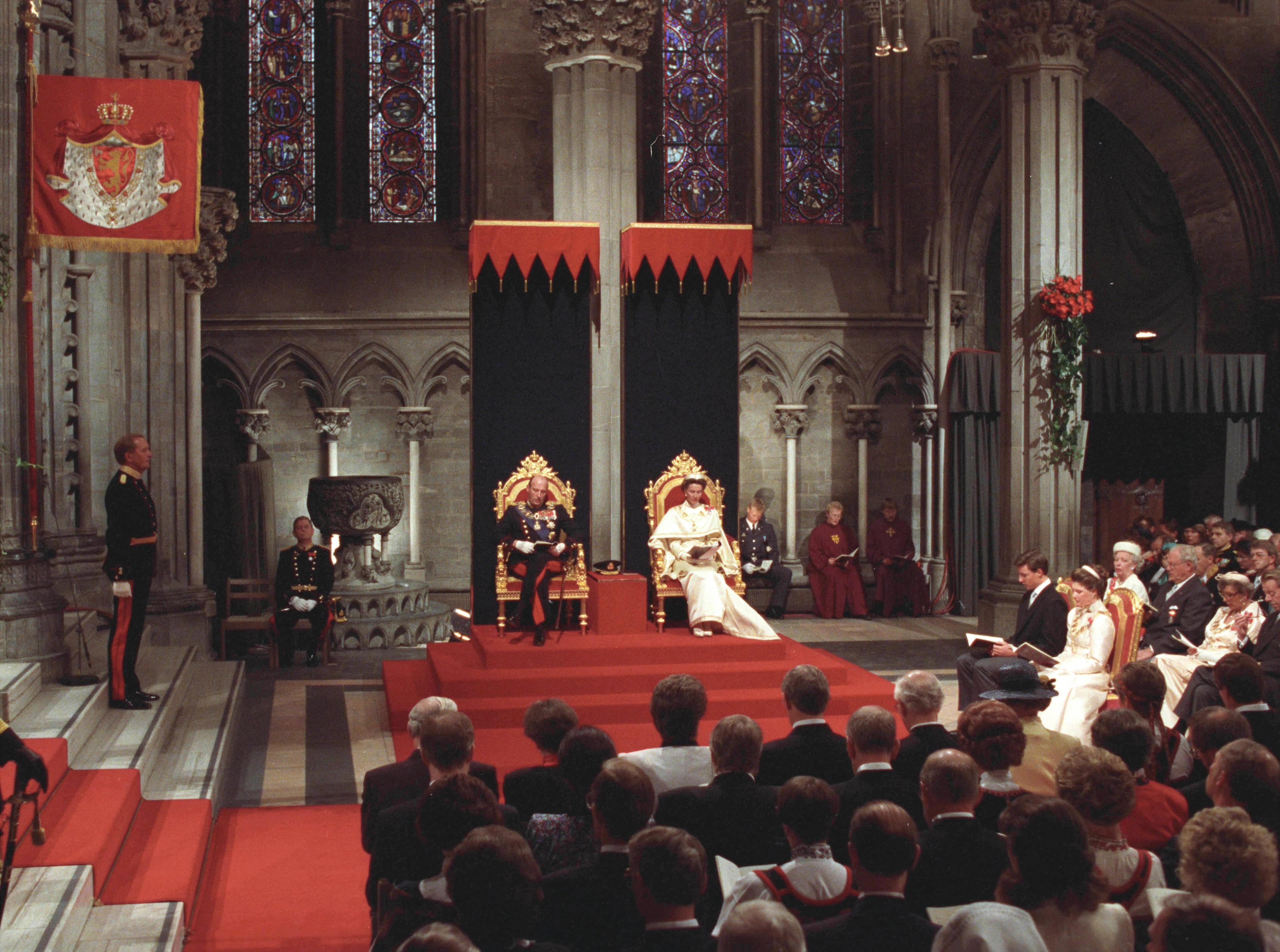 Oversiktsbilde der Kong Harald og Dronning Sonja sitter på kroningsstoler midt i bildet. Publikum i forgrunnen, Kronprins Haakon og Prinsesse Märtha Louise til høyre.