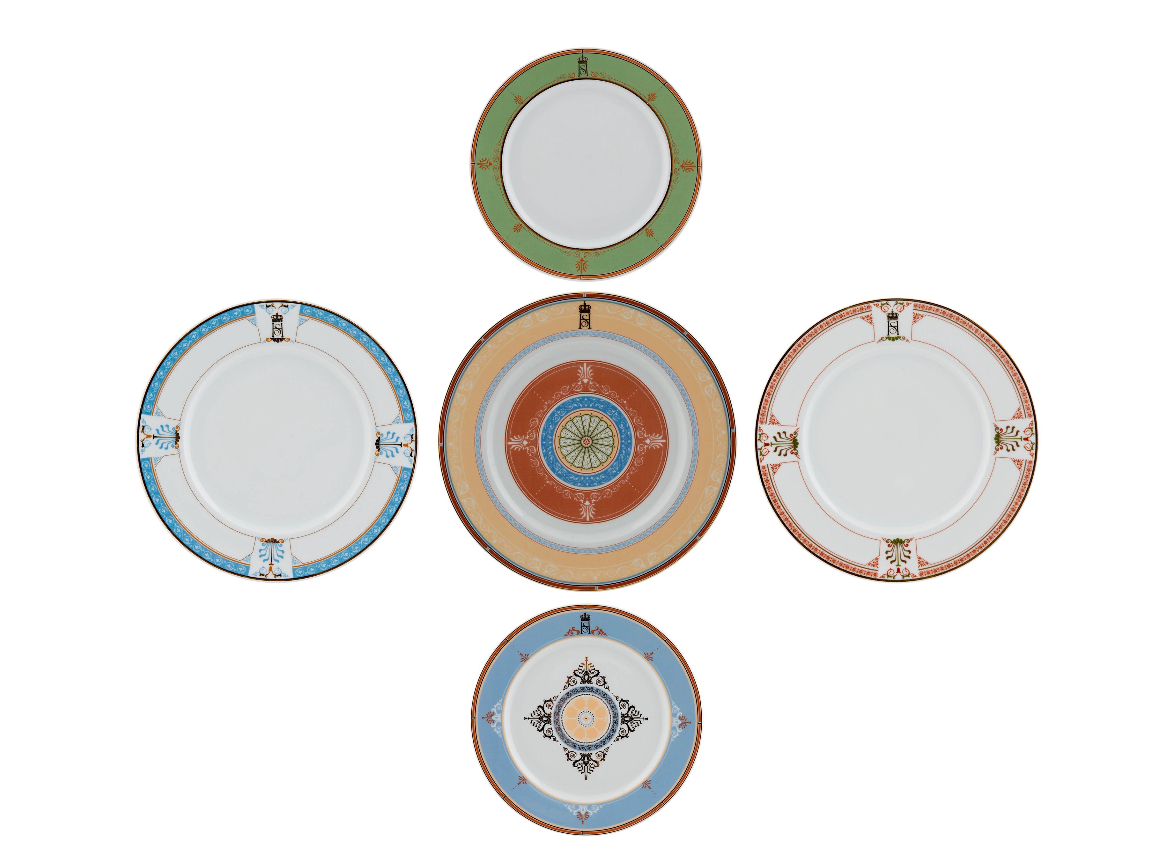 Fem tallerkener, alle med ulike dekor i ulike farger, men med felles utgangspunkt i dekoren i Slottets store spisesal.