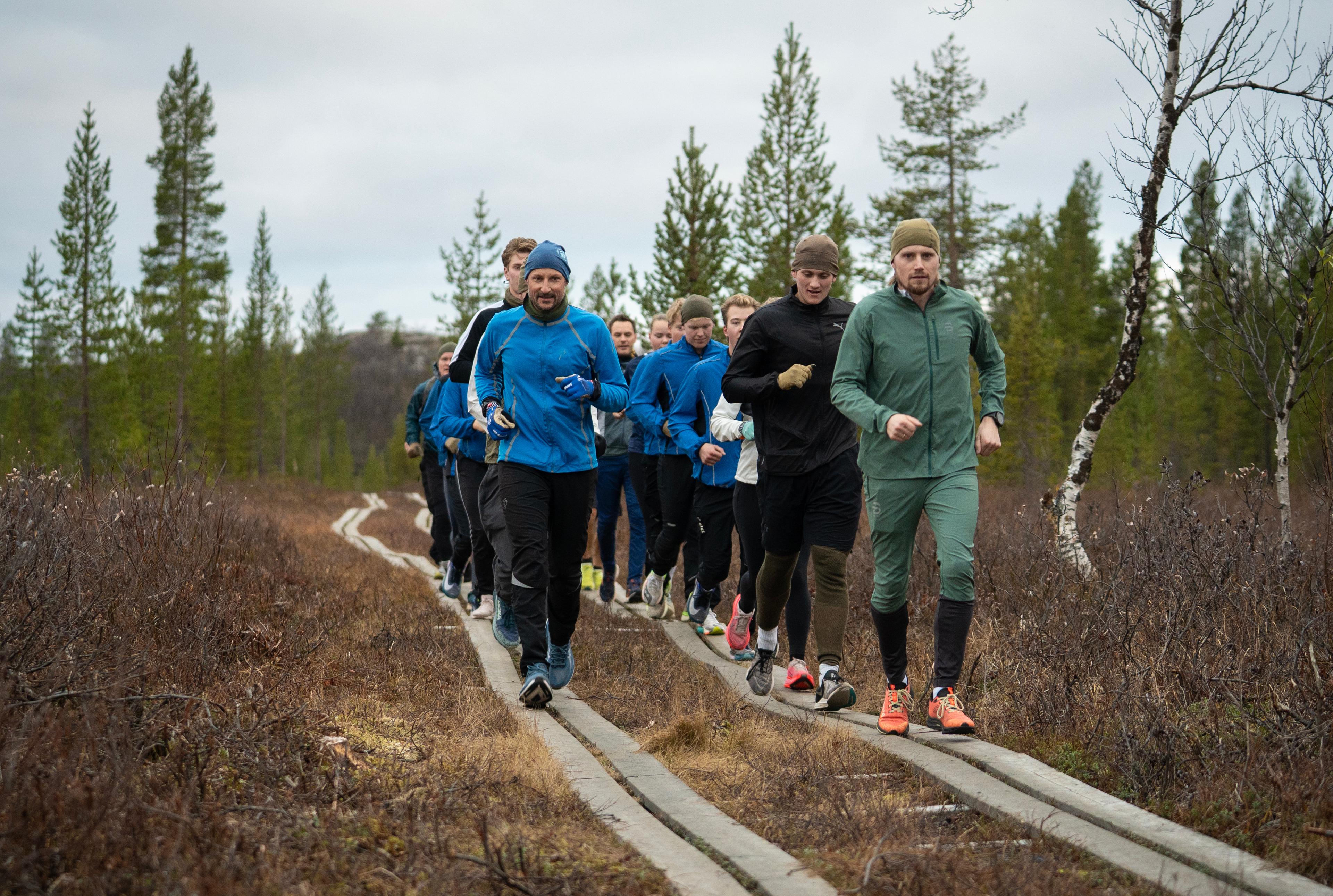 Kongen og de vernepliktige løper på to rekker. Kongen i front på den ene. Alle i treningstøy.
