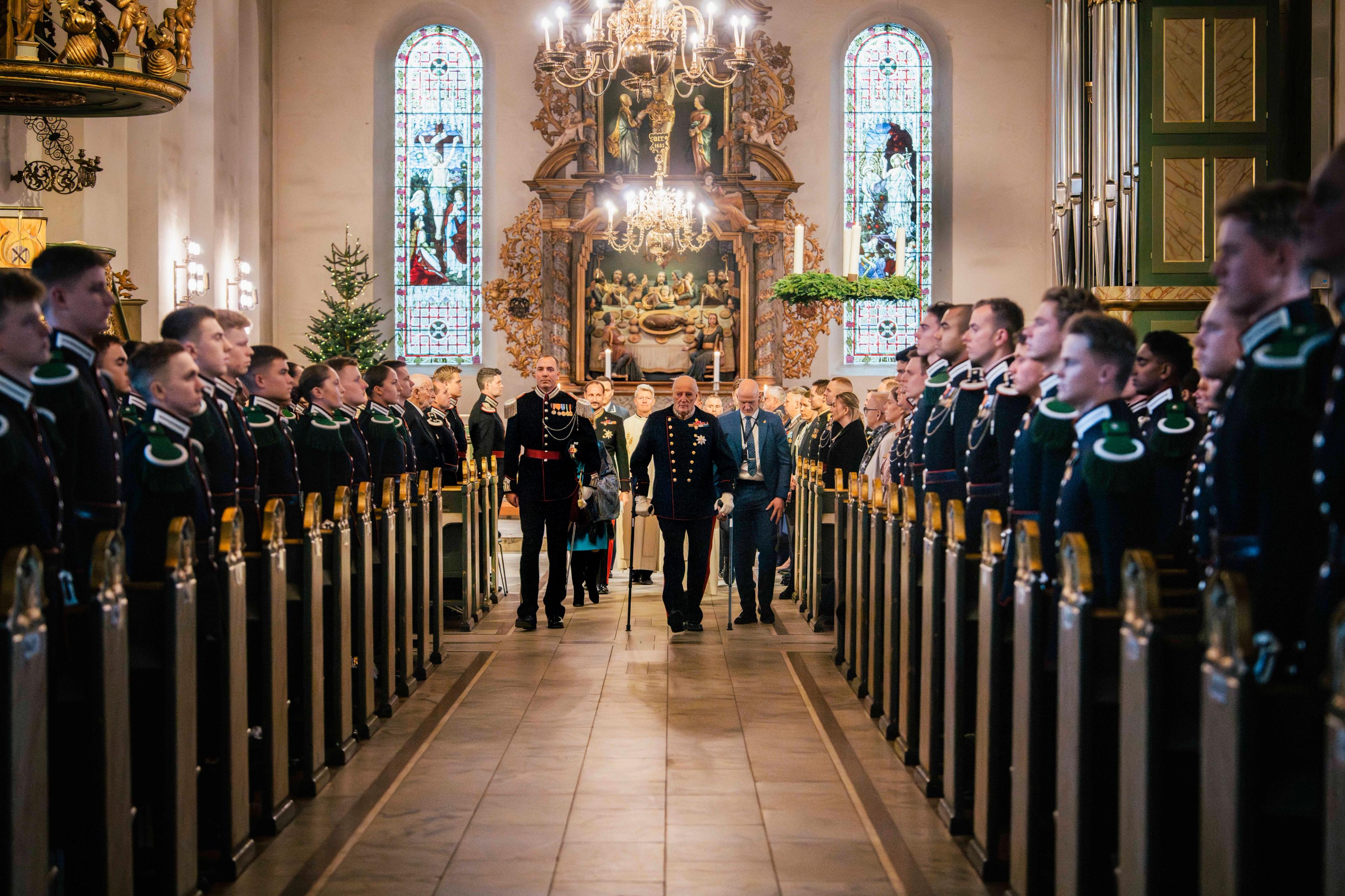 Kong Harald er på vei ut av Gardens kirkeparade sammen med gardesjef Henrik Hove. Langs sidene står garden oppstilt.