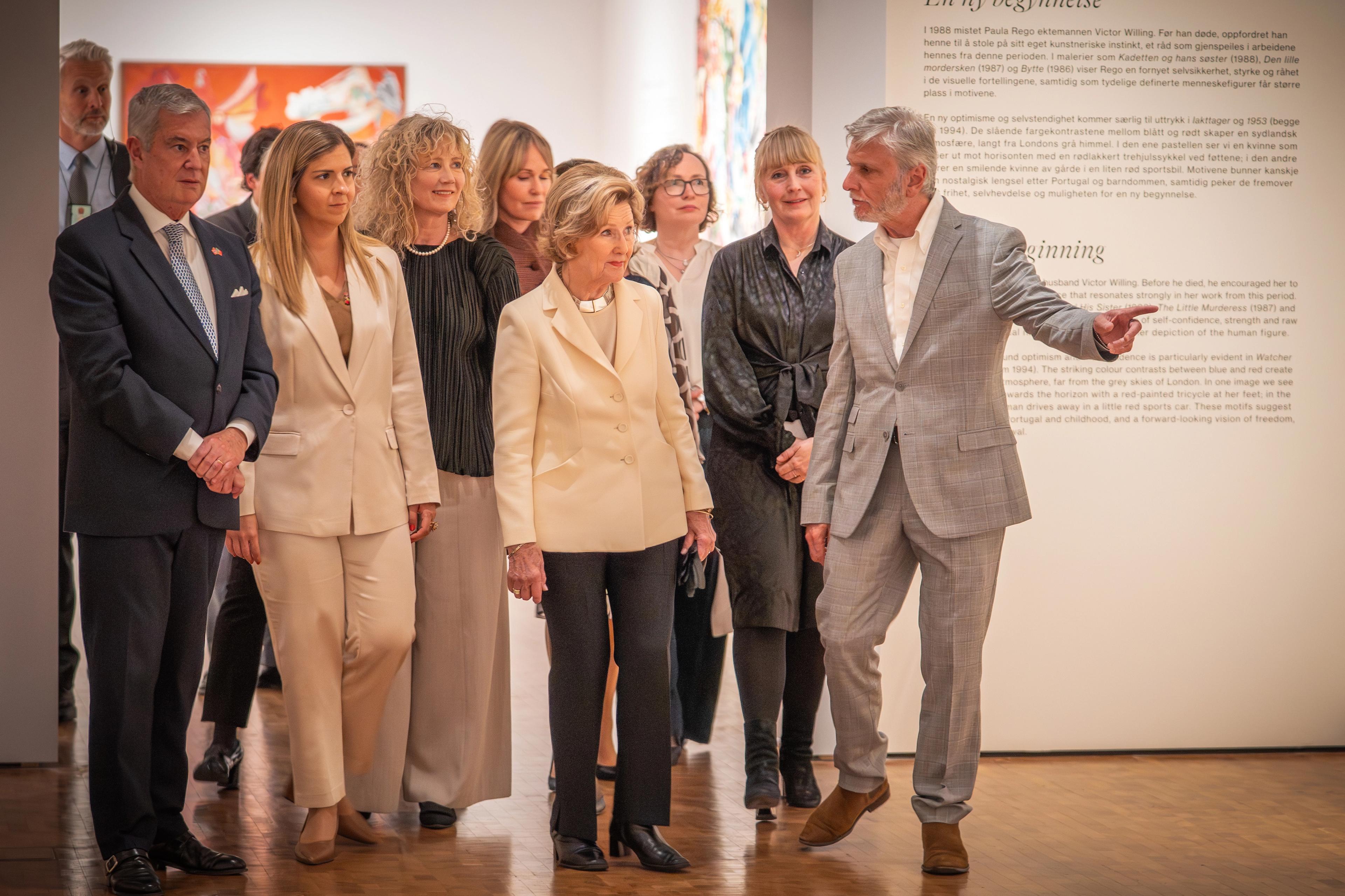 Nick Willing peker på et verk i utstillingen mens han ser i retning Dronningen og resten av følget.