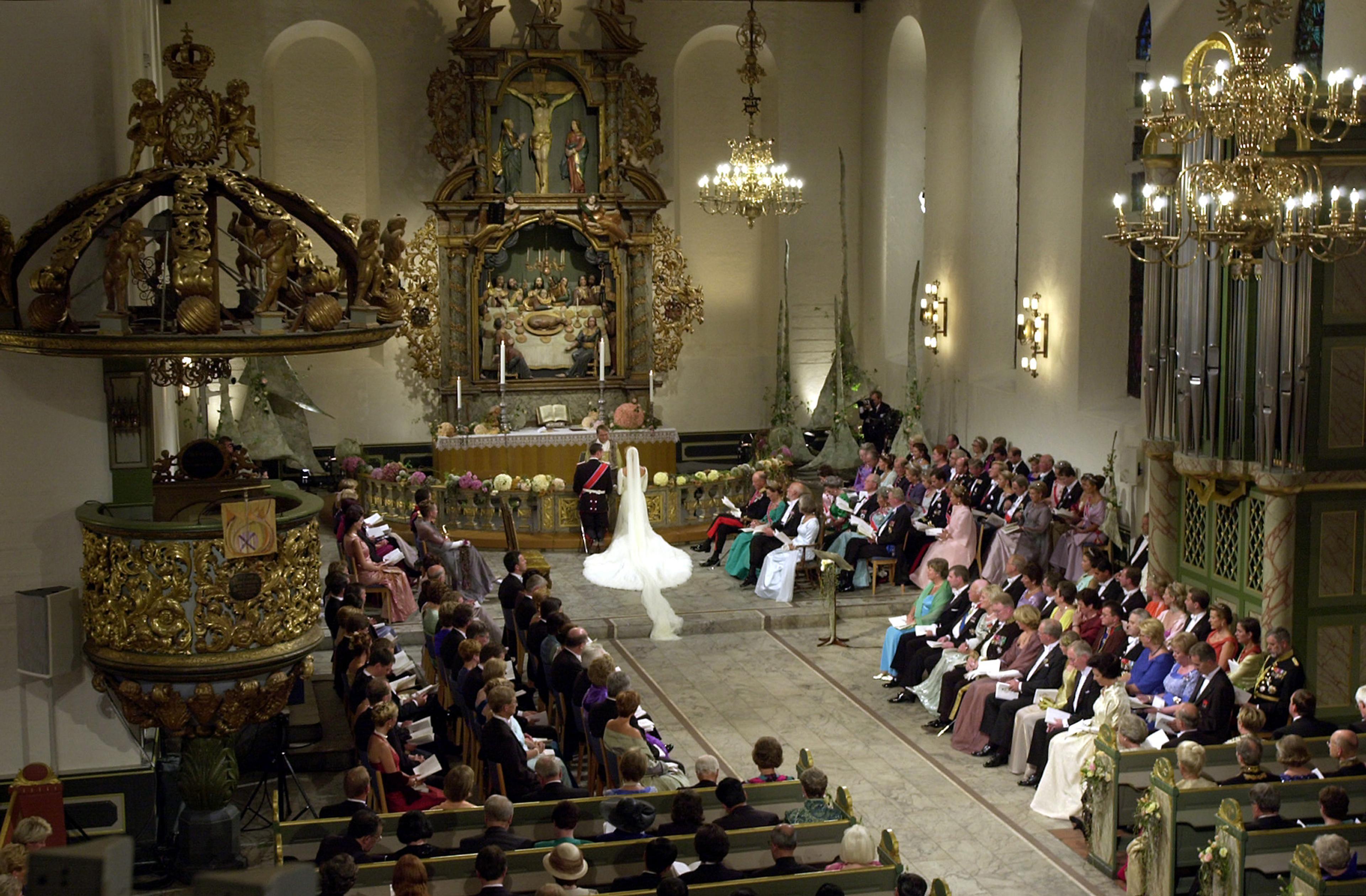 Kronprinsparet knele ved alteret foran biskopen. Brullupsgjestene fyller benkeradene.