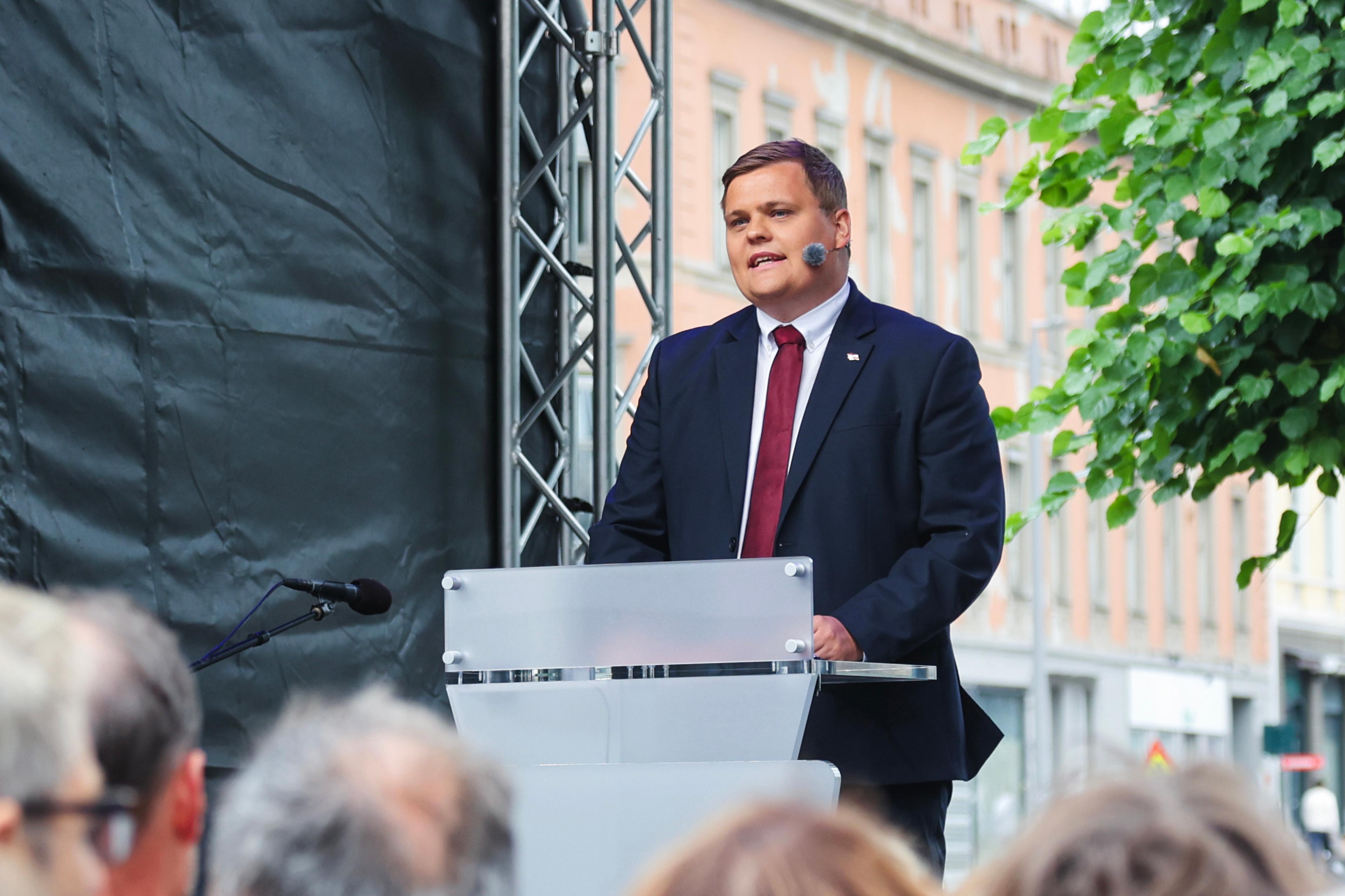 Skjervø i dress ved talerstolen foran minnesmerket.