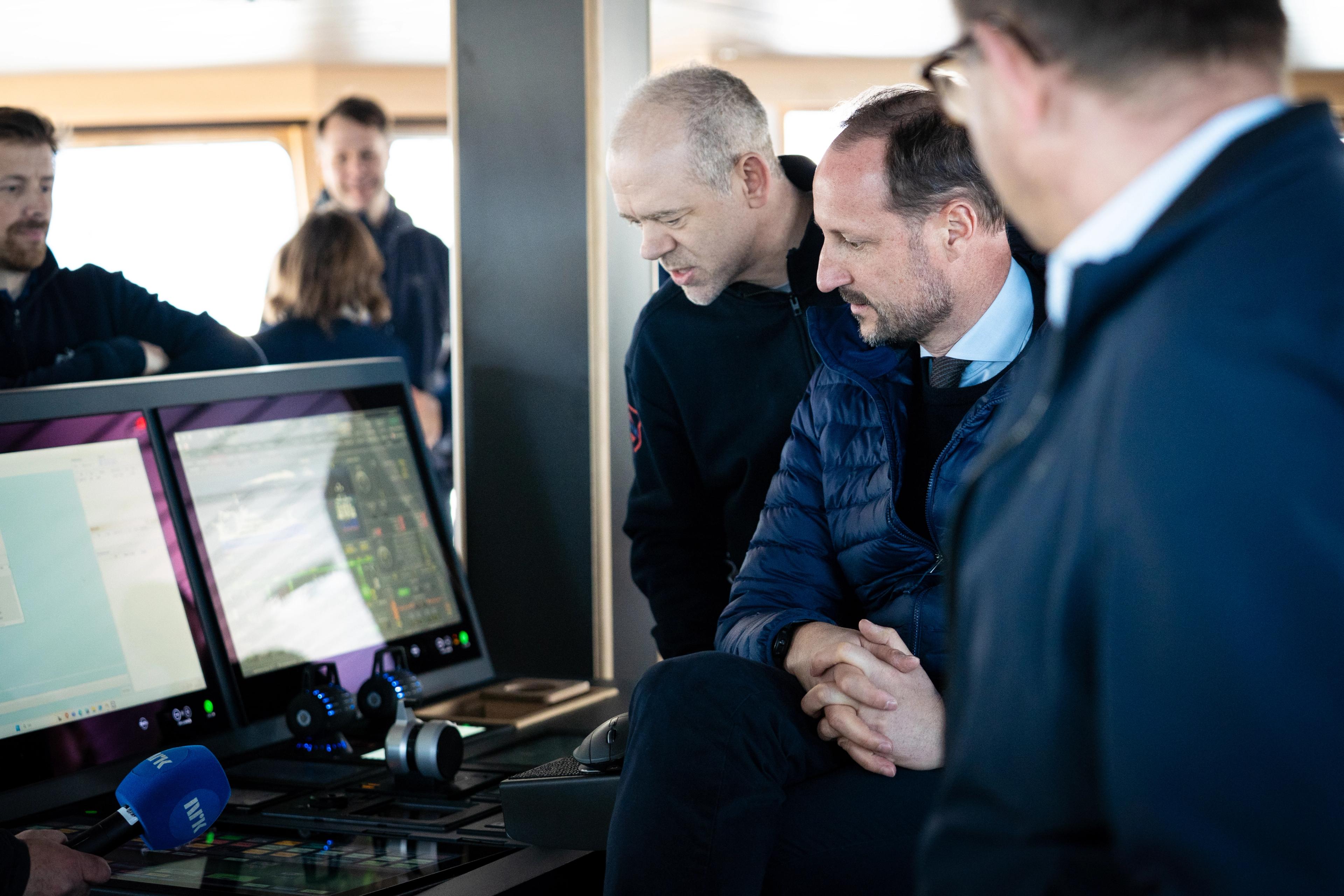 Kronprinsen og vertskapet er samlet rundt skjermer og instrumenter på broa.