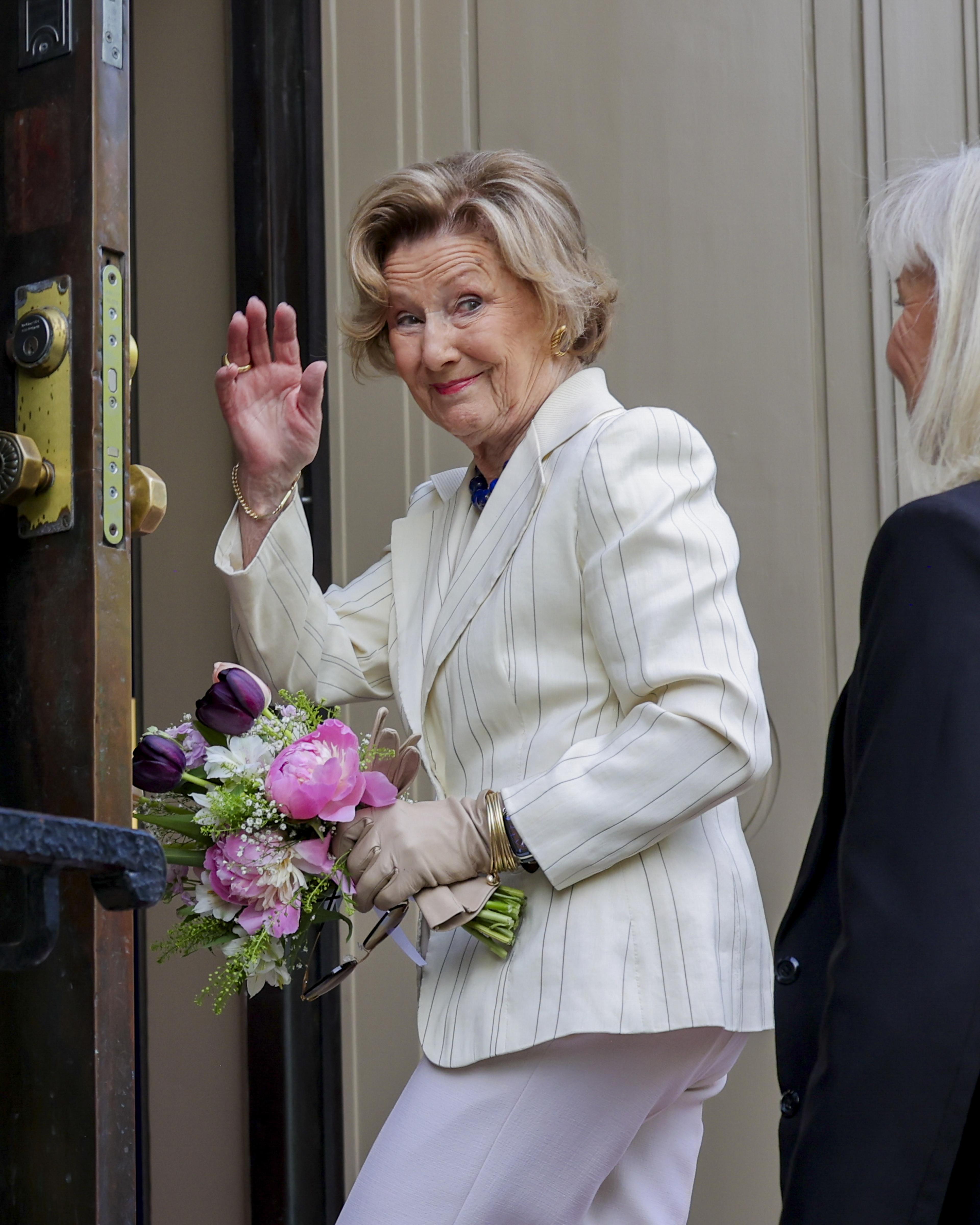 Dronning Sonja vinker på vei inn døra.