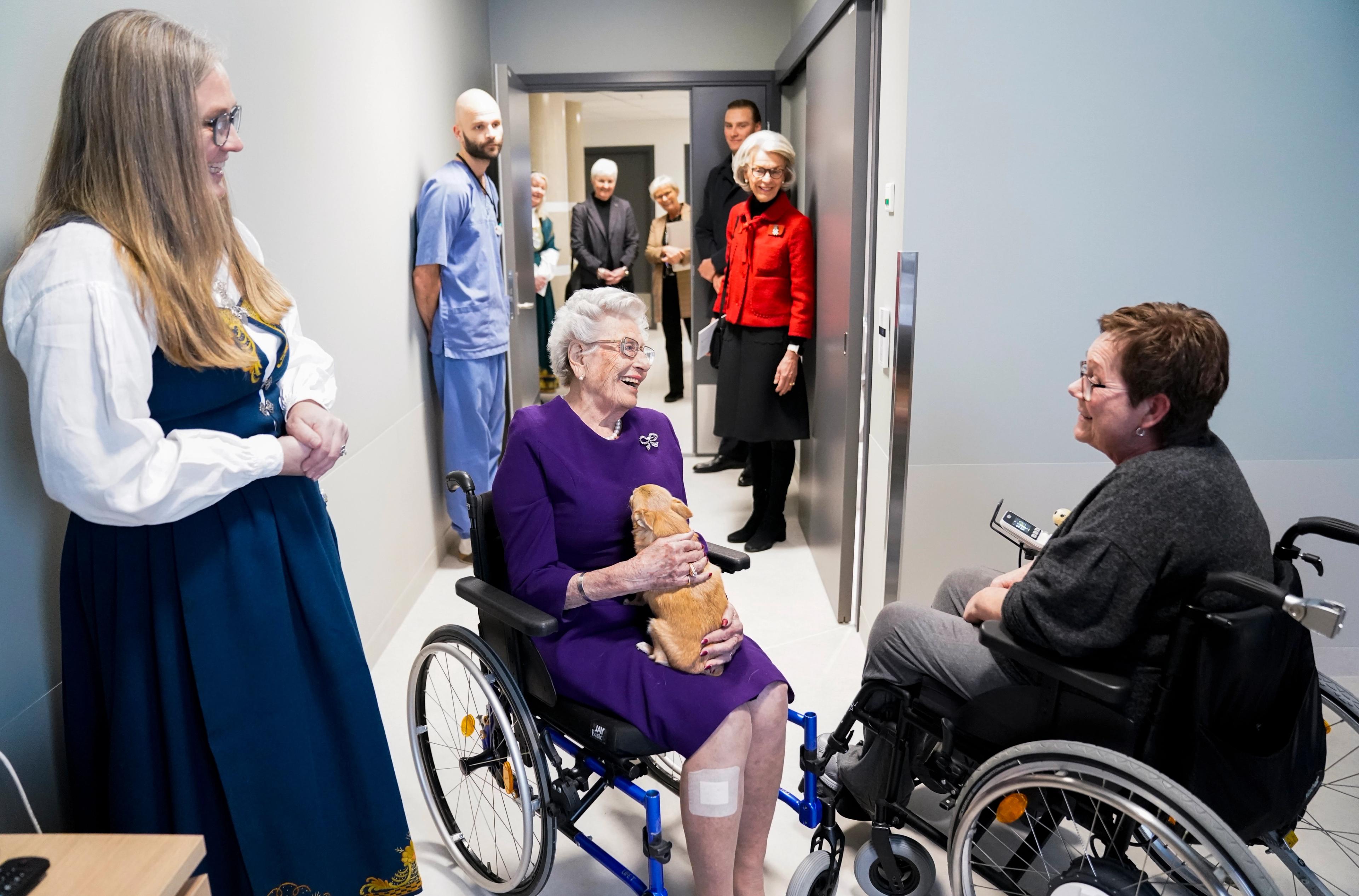 Prinsesse Astrid i samtale med en av beboerne på helsehuset - begge i hver sin rullestol.