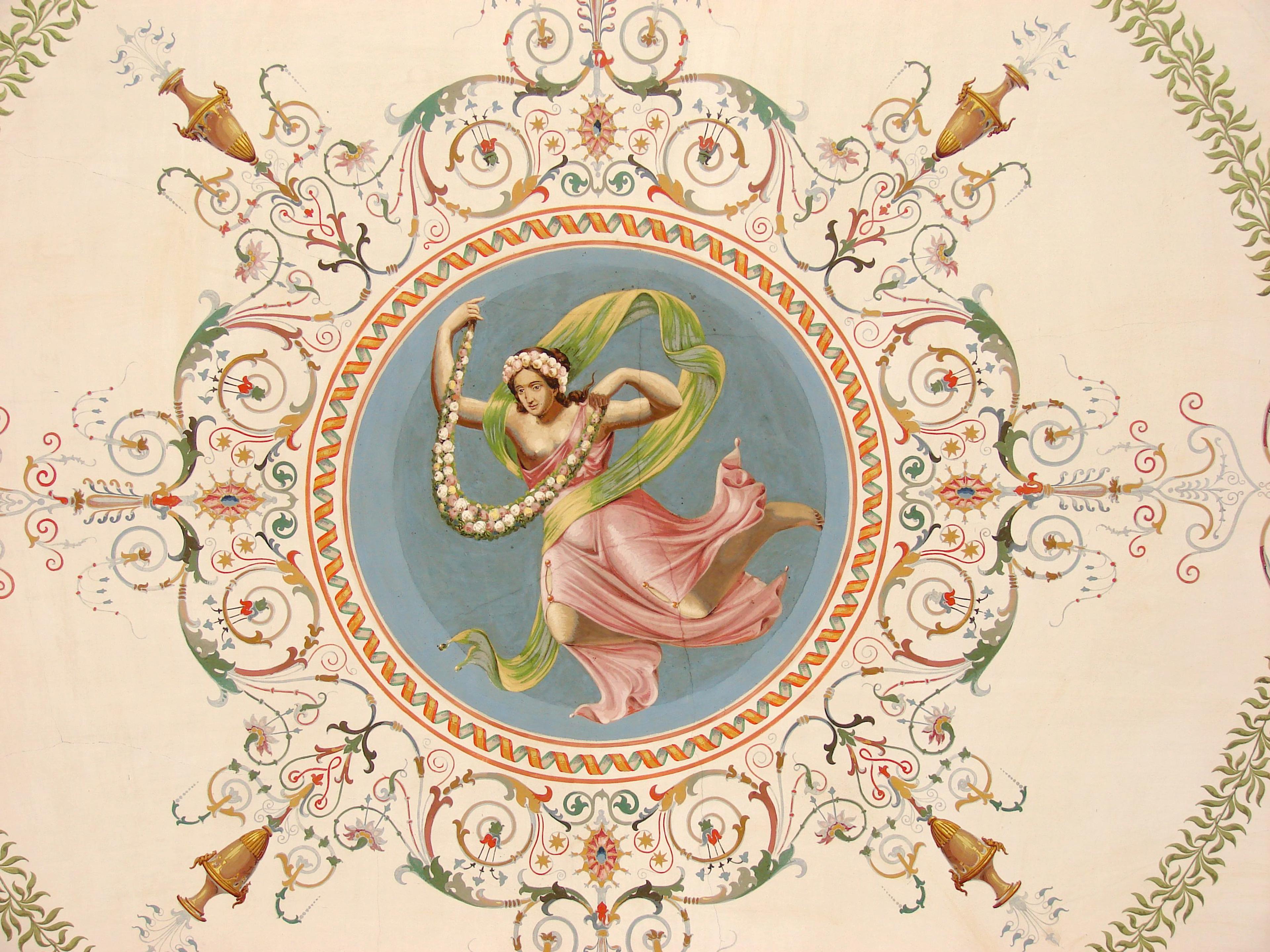 En flyvende skikkelse med blomsterkrans og flagrende gavanter er gjengitt på blå bakgrunn med border omkring.