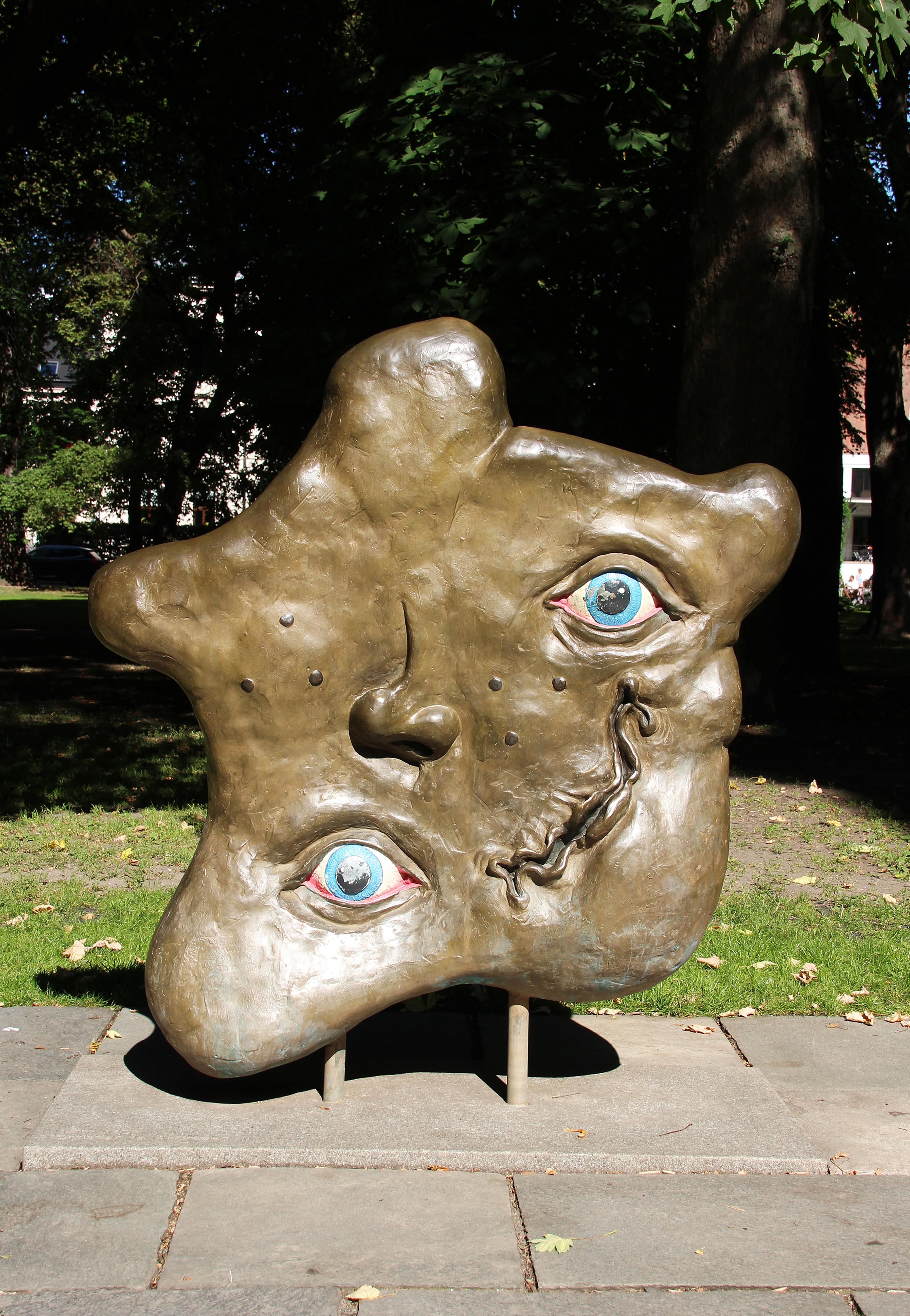 Et ansikt uten ansikts form. To blå øyne, nese og krøllete munn befinner seg på tilsynelatende tilfeldige steder.