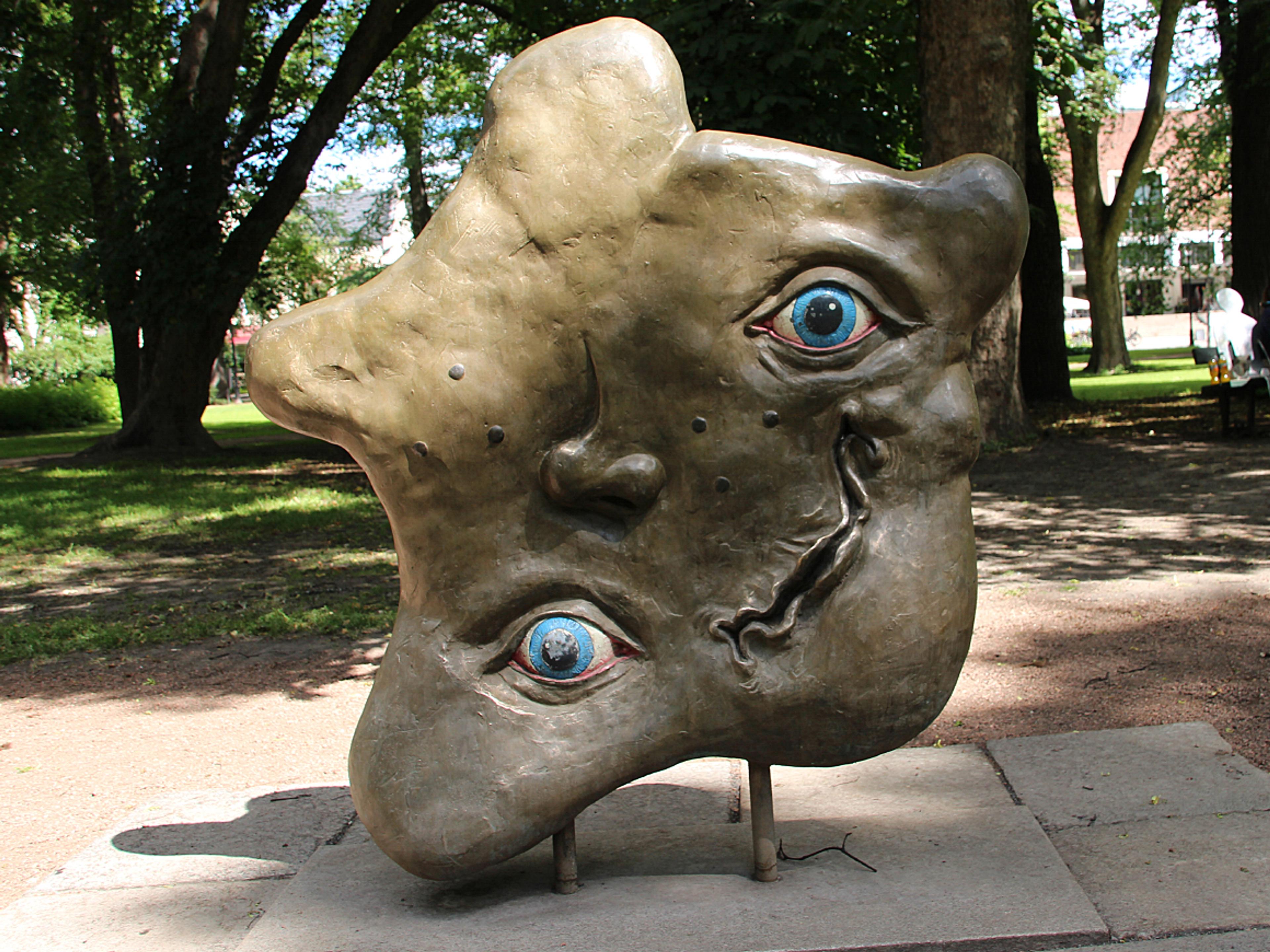 Et ansikt uten ansikts form. To blå øyne, nese og krøllete munn befinner seg på tilsynelatende tilfeldige steder.