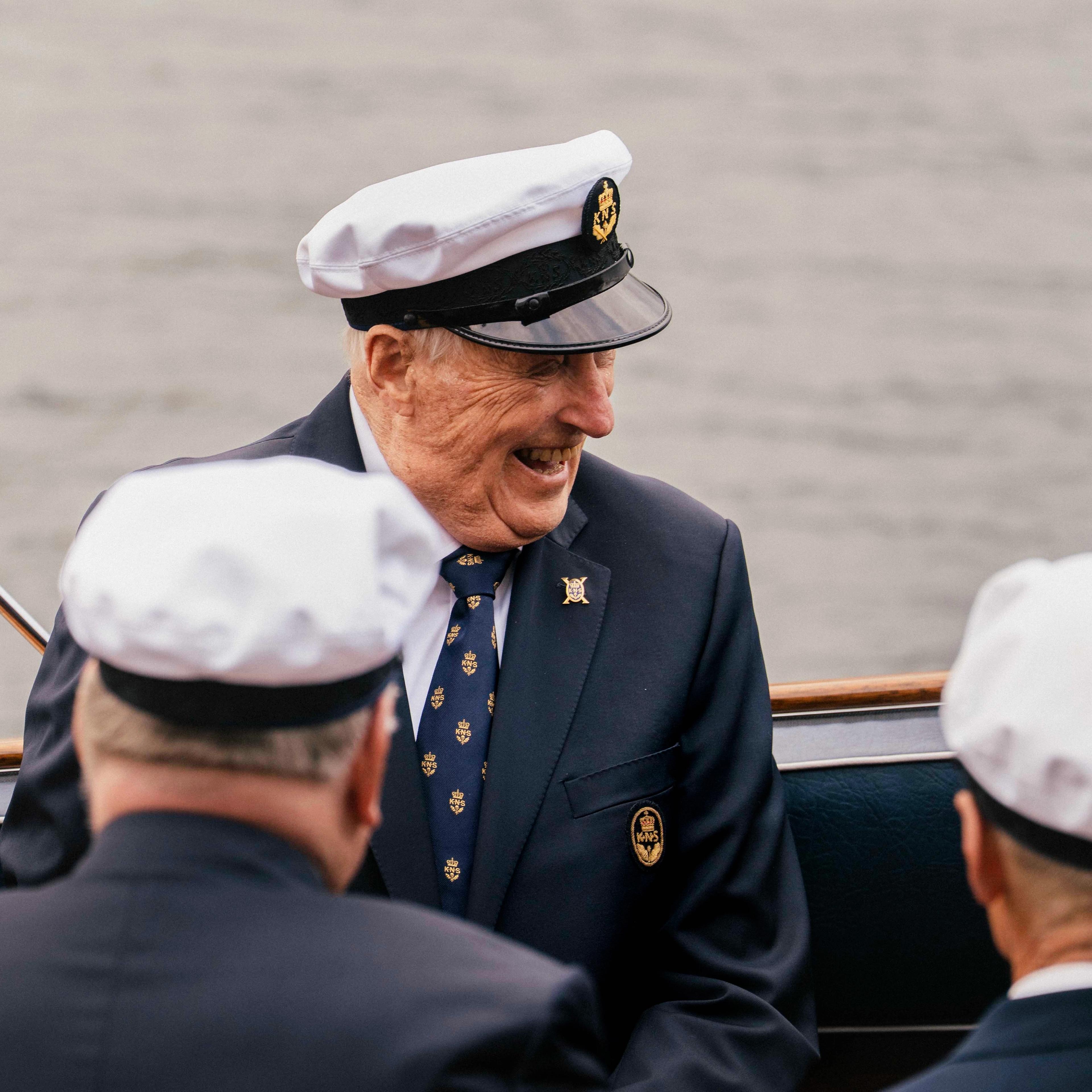 Kong Harlad sitter i Kongebåten Stjernen med et stort smil