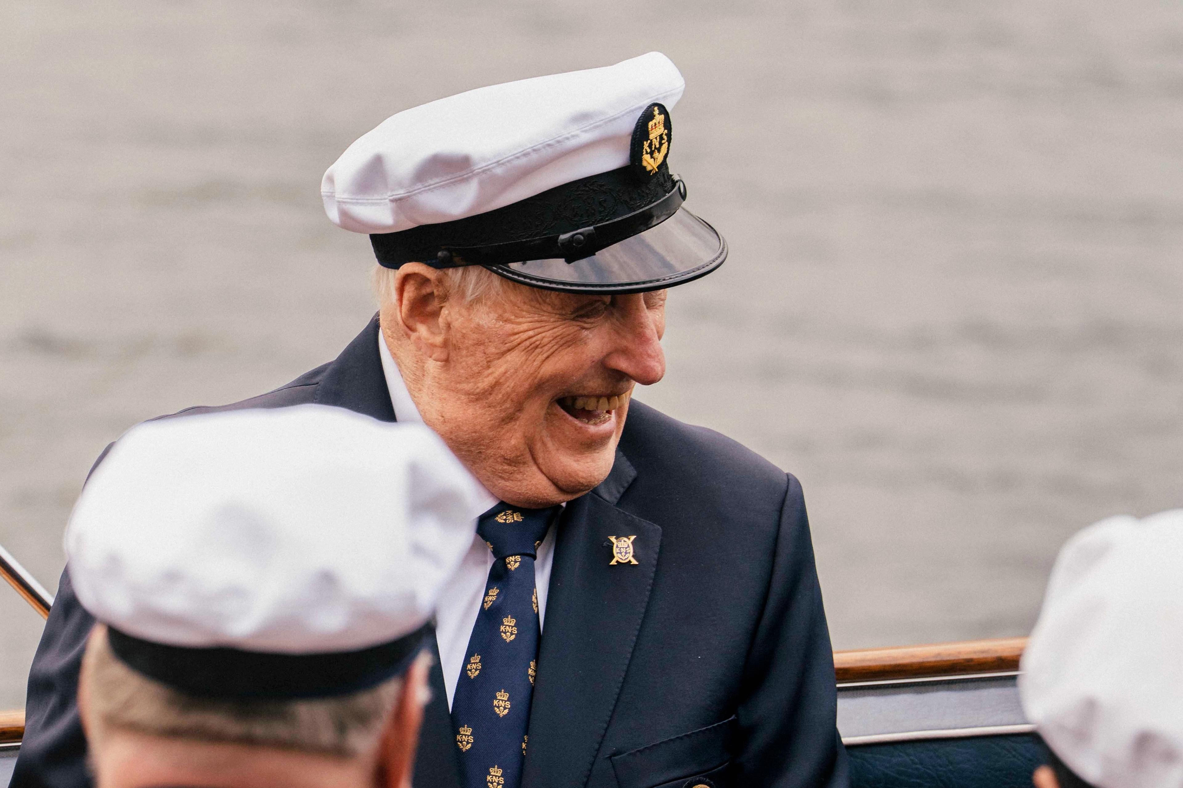 Kong Harlad sitter i kongebåten Stjernen med et stort smil.