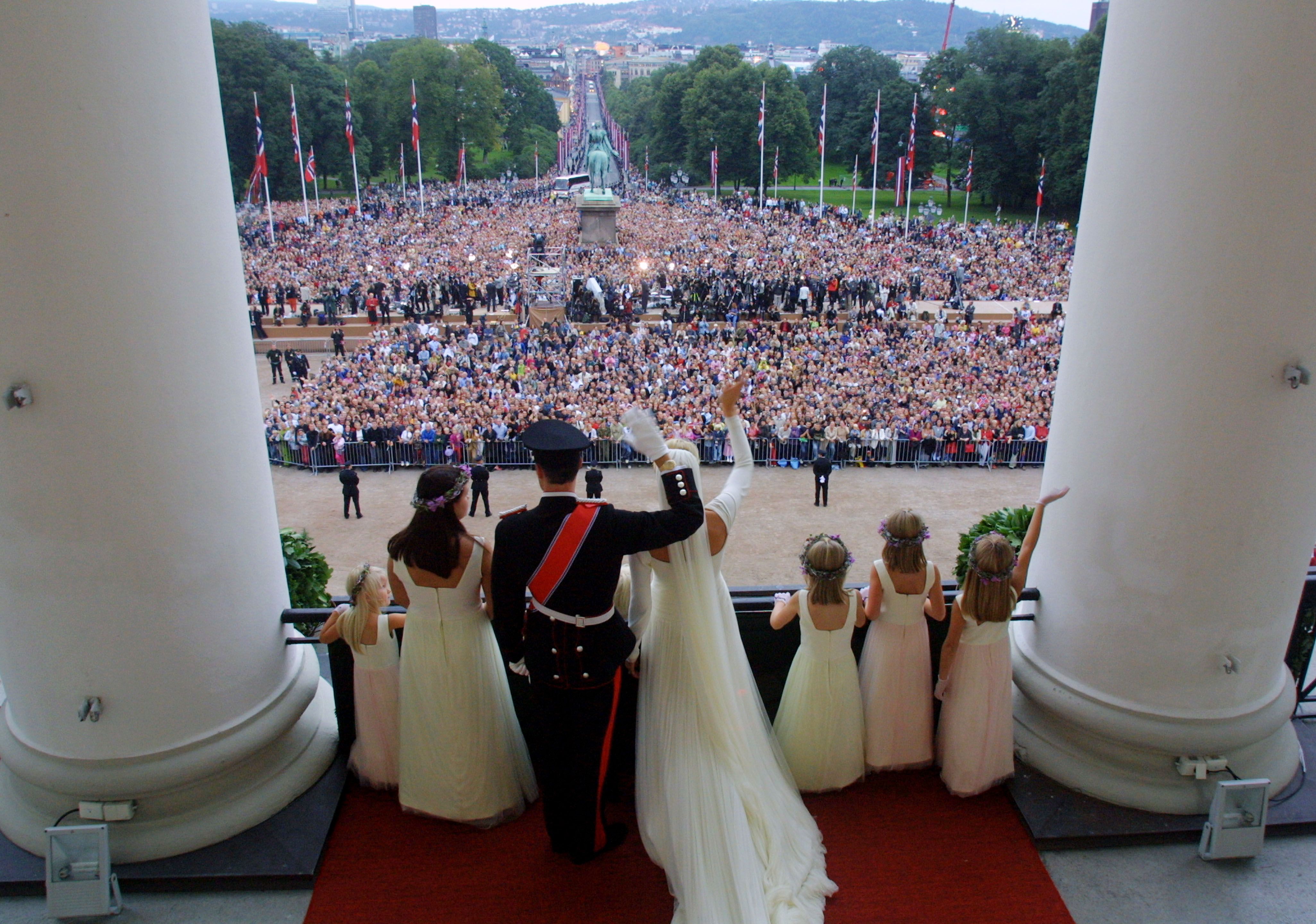 Kronprinsparet og deres brudepiker er avbildet bakfra og vi ser utover Slottsplassen. og de mange menneskene som er samlet der.