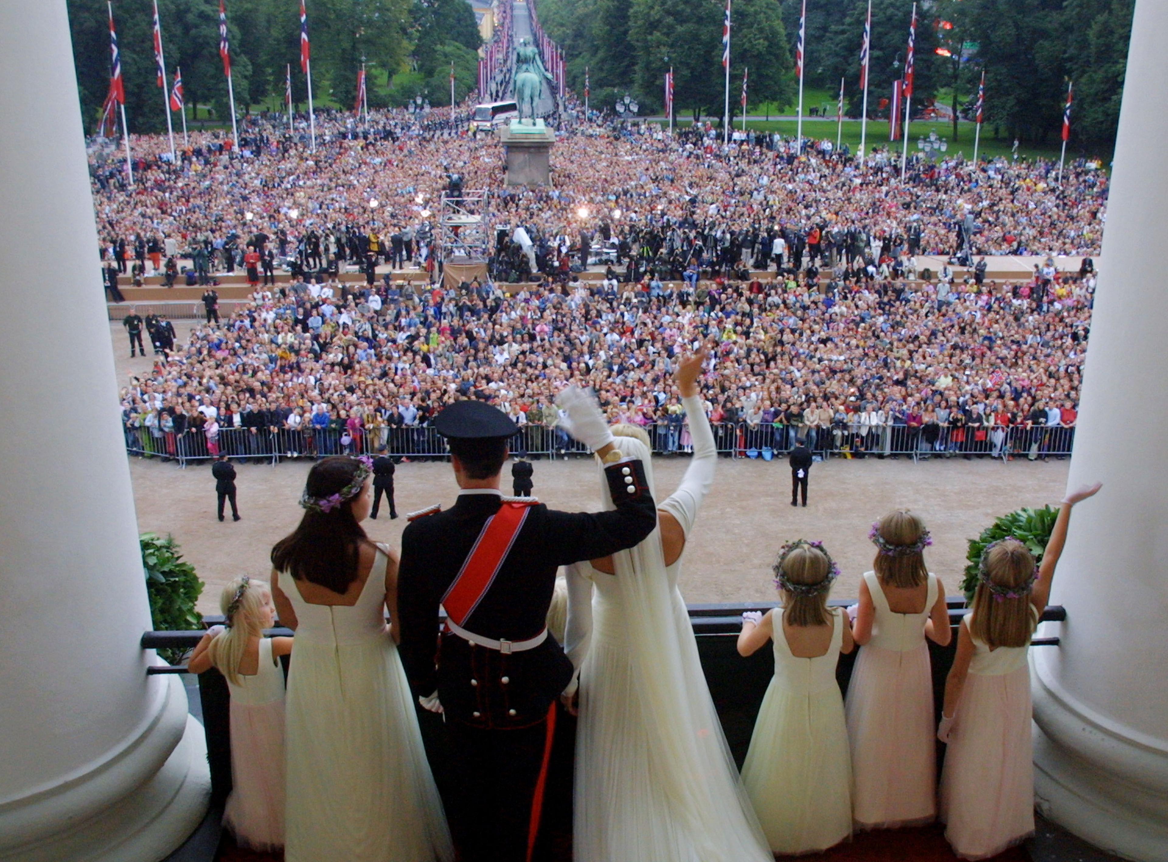 Kronprinsparet og deres brudepiker er avbildet bakfra og vi ser utover Slottsplassen. og de mange menneskene som er samlet der.