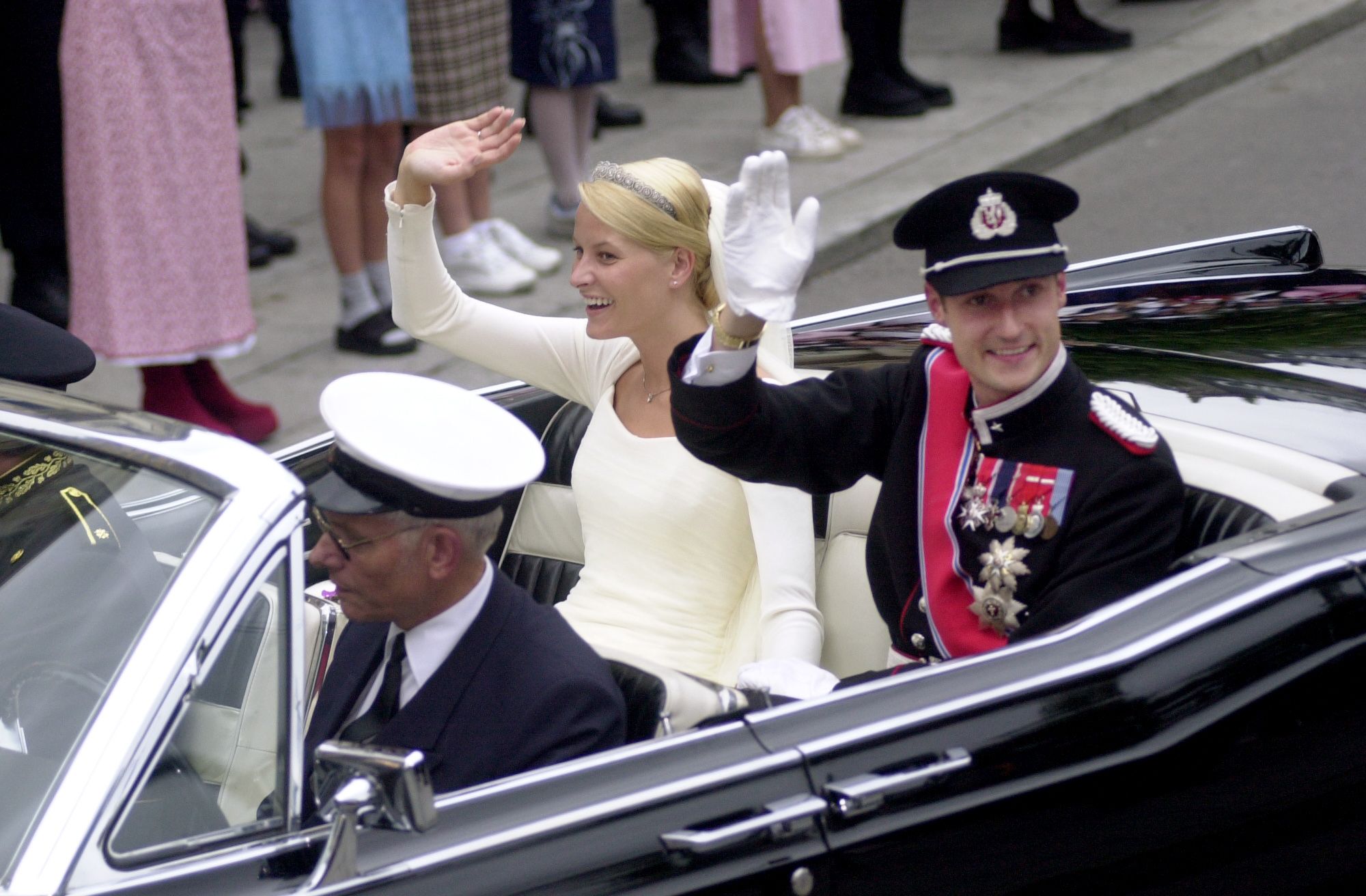 Brudeparet vinker til alle menneskene langs gaten.