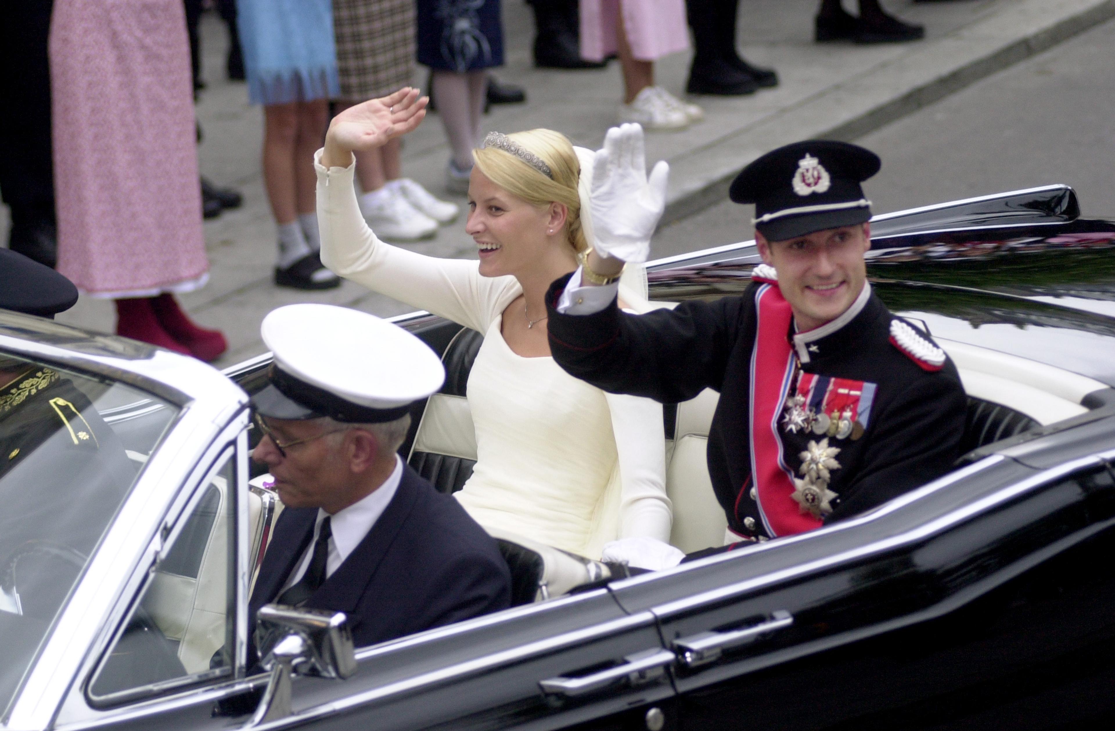 Brudeparet vinker til alle menneskene langs gaten.