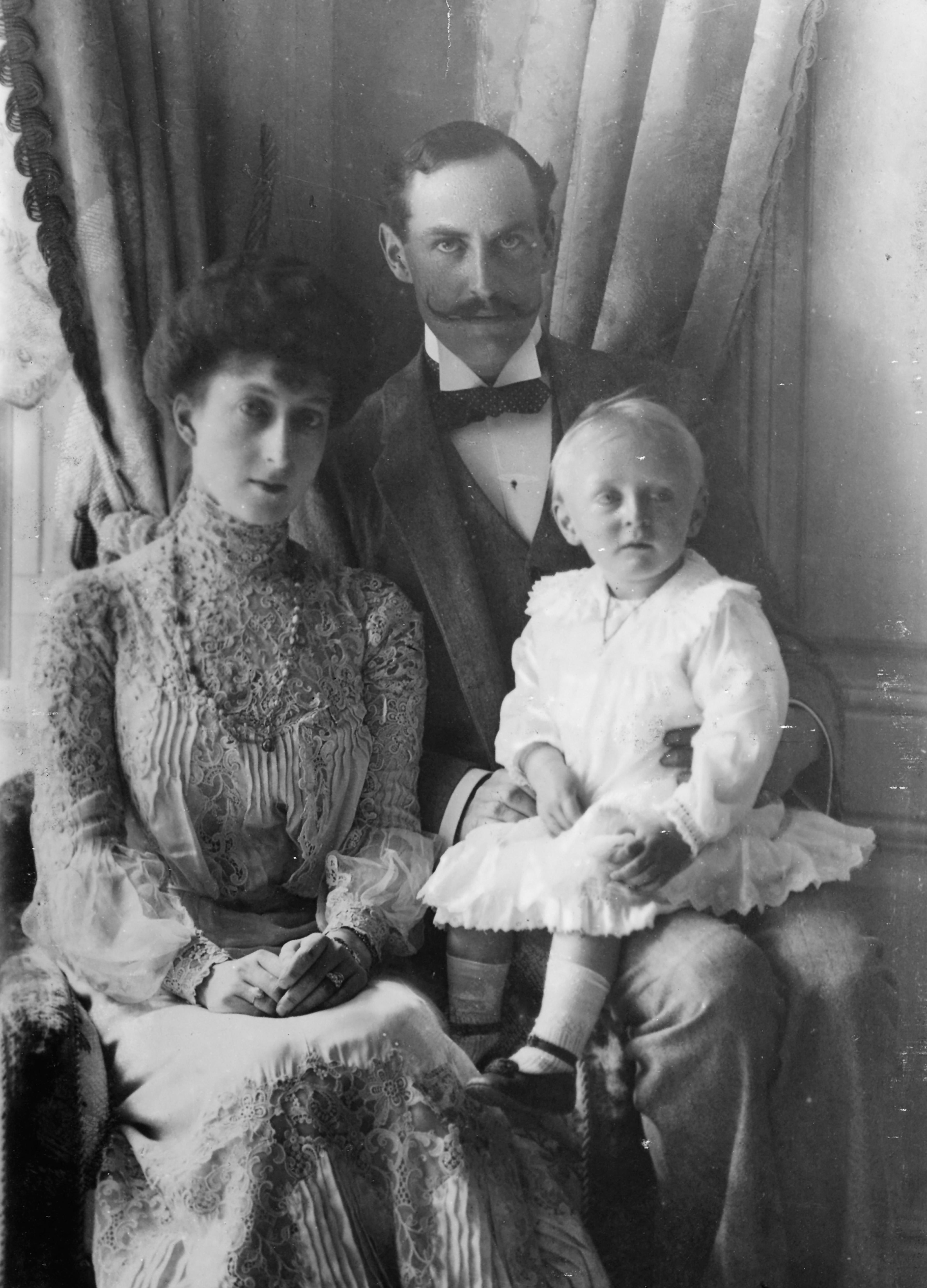 Kong Haakon og Dronning Maud i 1905. Kongen har den unge Kronprins Olav på fanget.