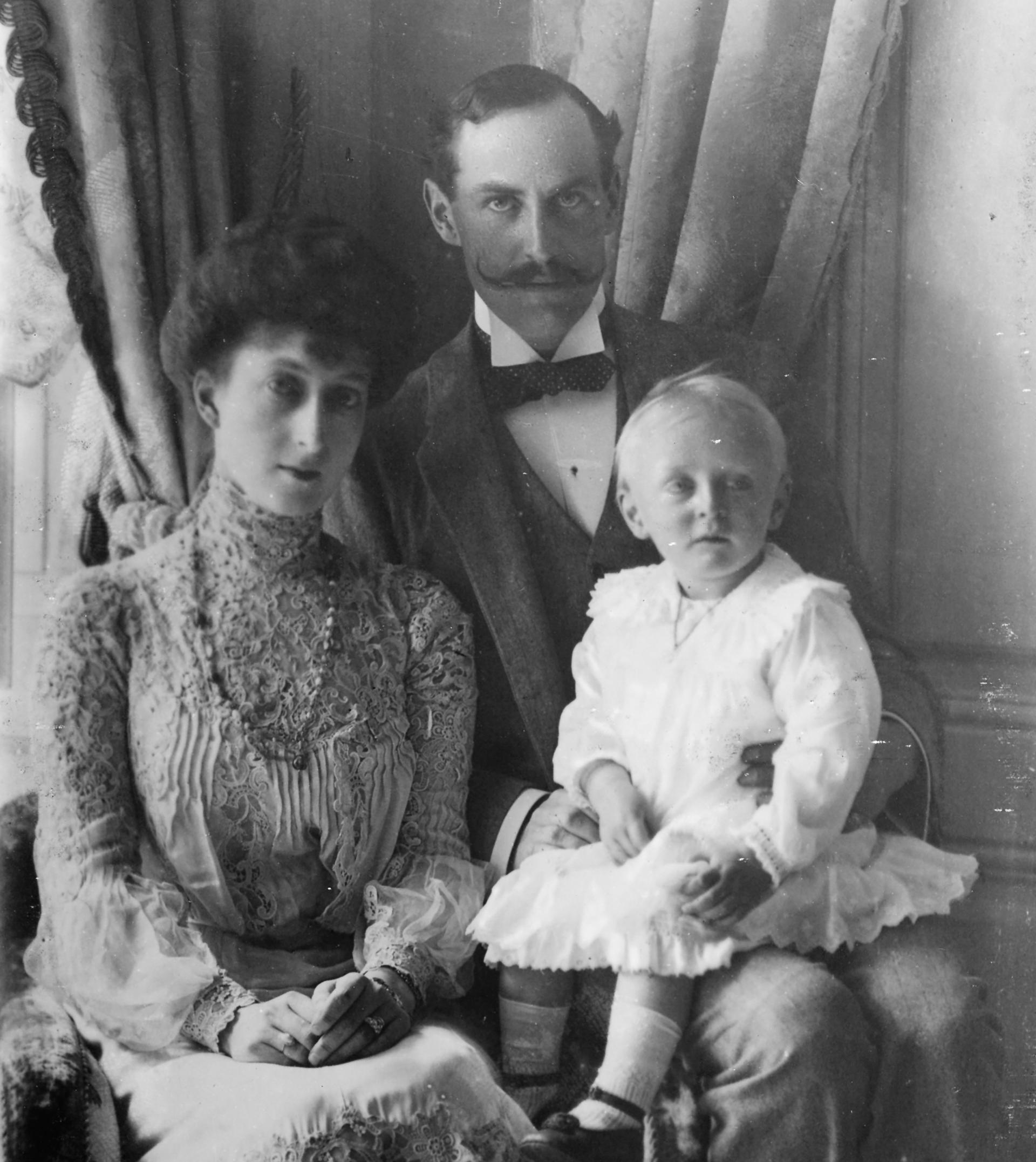 Kong Haakon og Dronning Maud i 1905. Kongen har den unge Kronprins Olav på fanget.