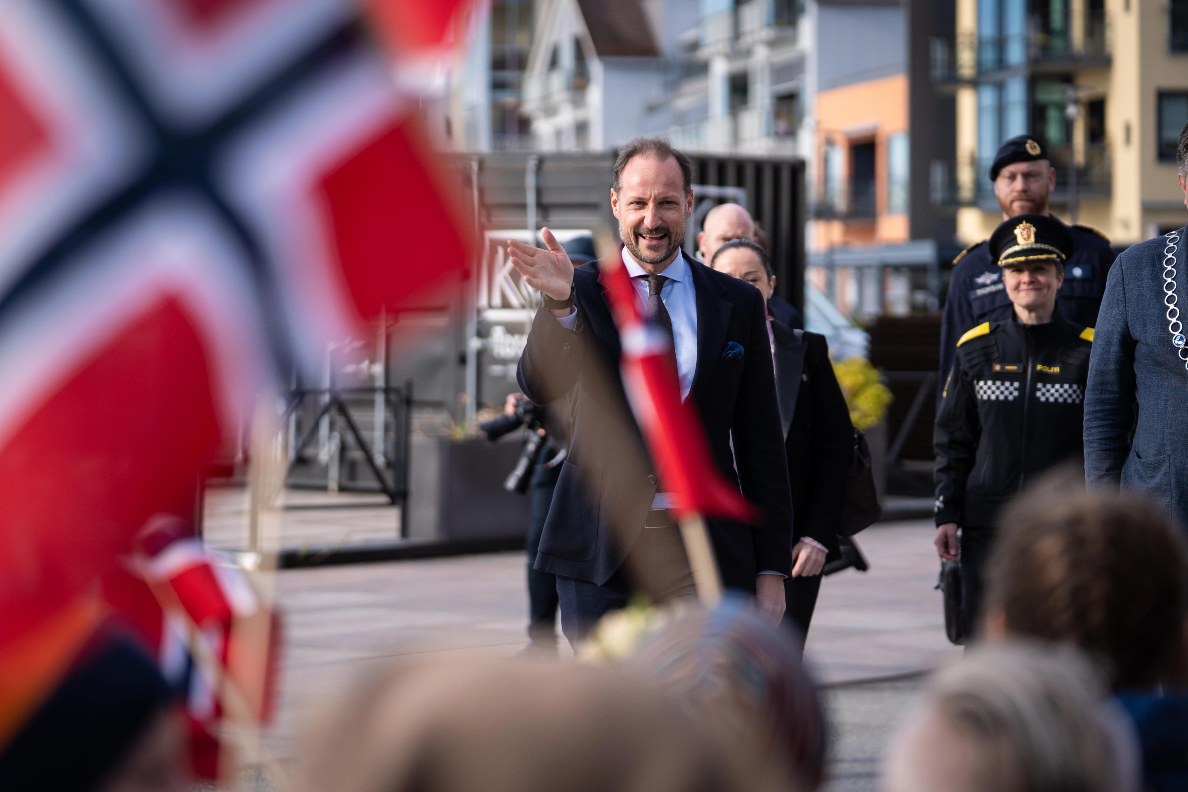 Kronprinsen kommer gående mot barn som står med norske flagg.