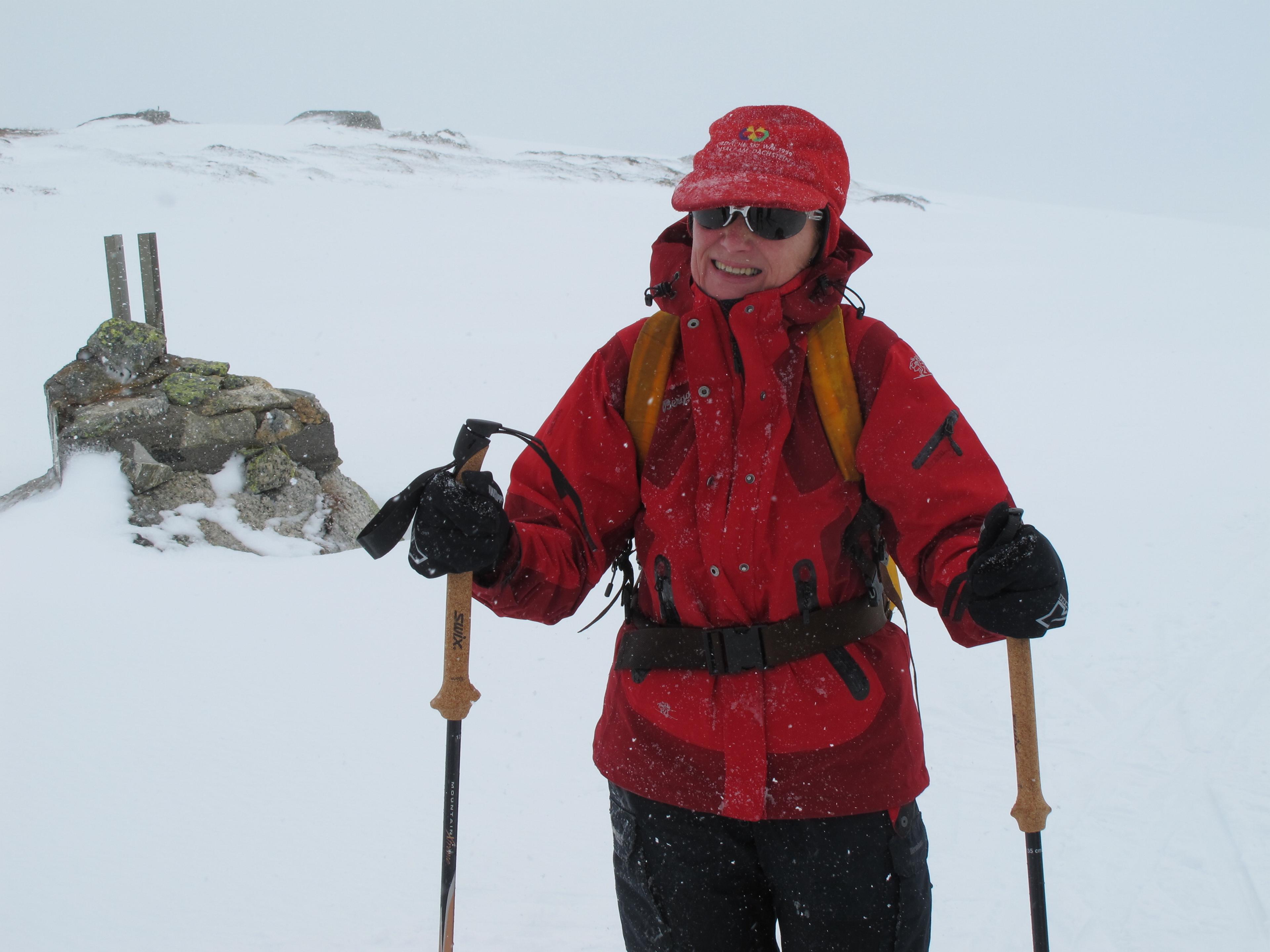 Dronning Sonja er godt pakket inn turklær på fjellet, men sikten er dårlig. Det snør.
