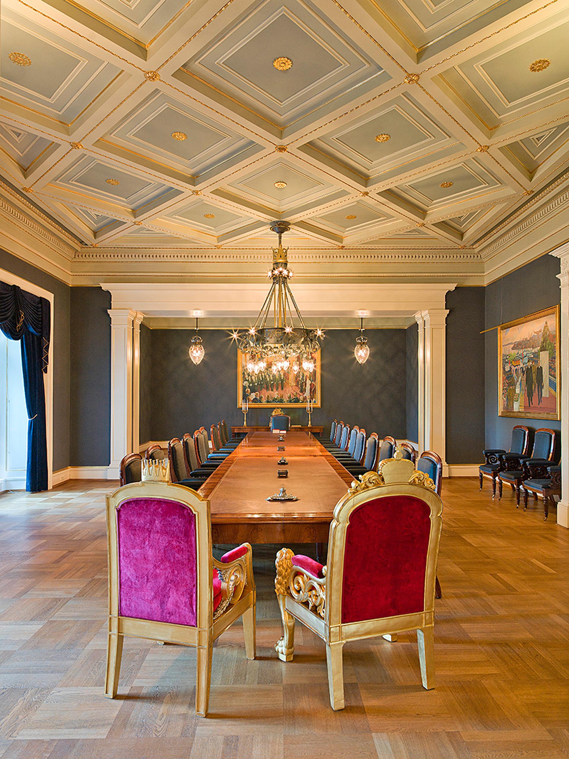 En tom statsrådsal sett fra enden av bordet der Kongen har sin plass.
