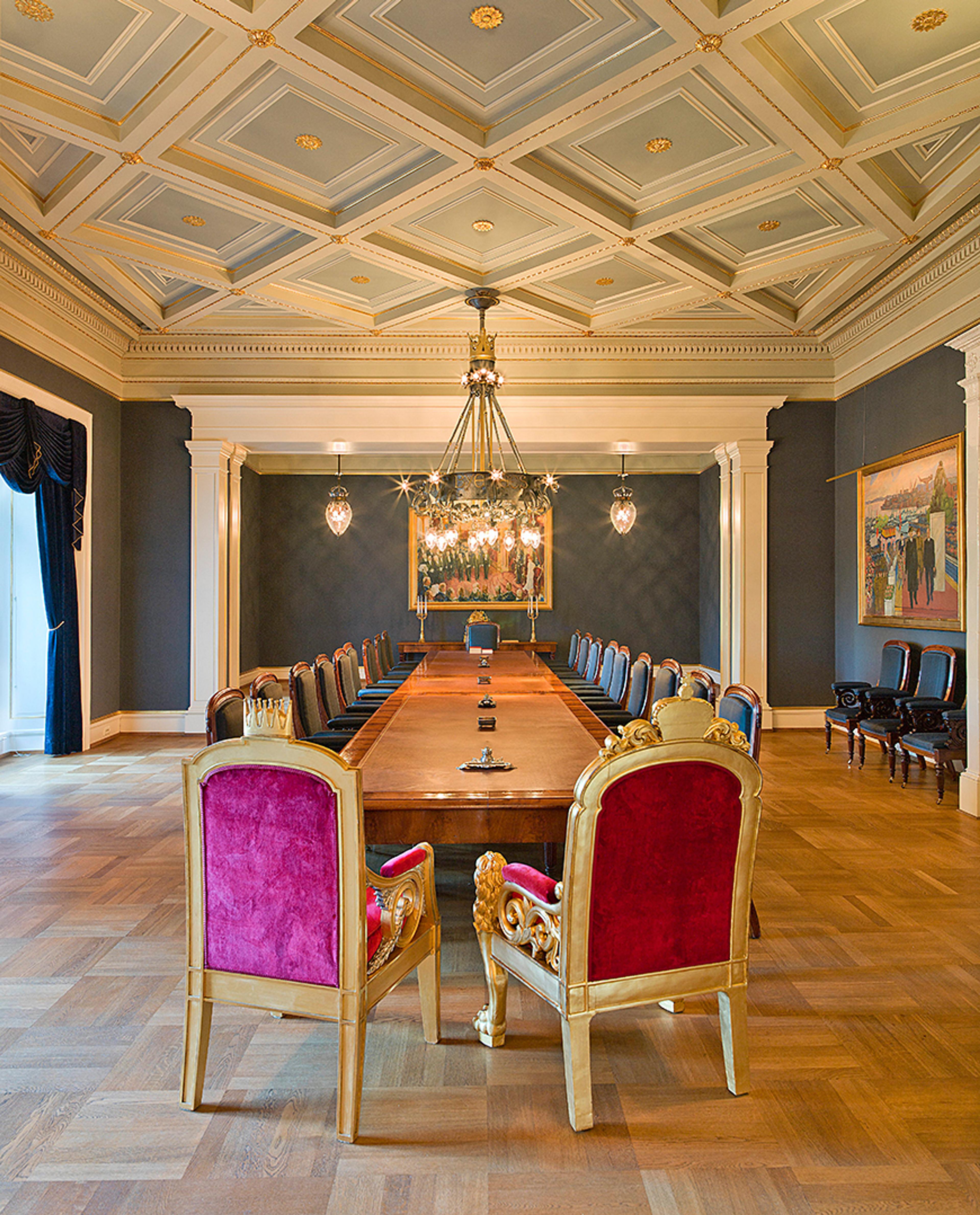 En tom statsrådsal sett fra enden av bordet der Kongen har sin plass.