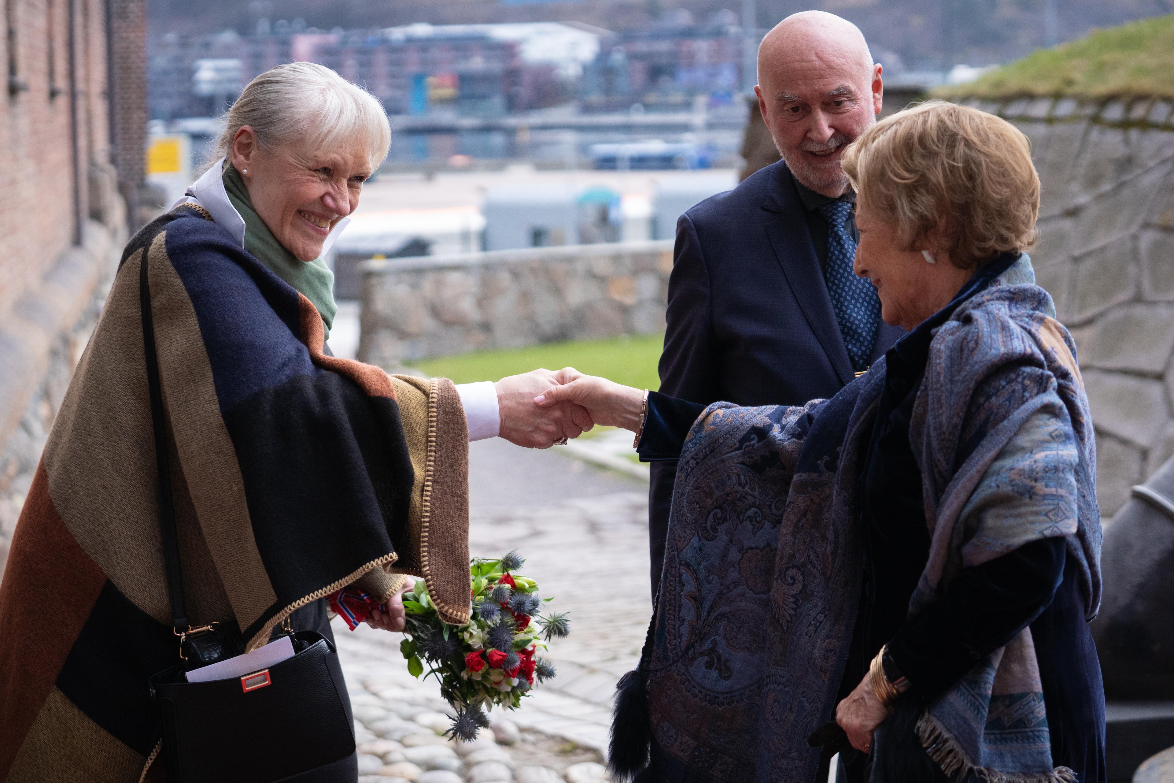 Dagleg leiar helsar på Dronning Sonja utandørs på Akershus festning. Styreleiar står i bakgrunnen.