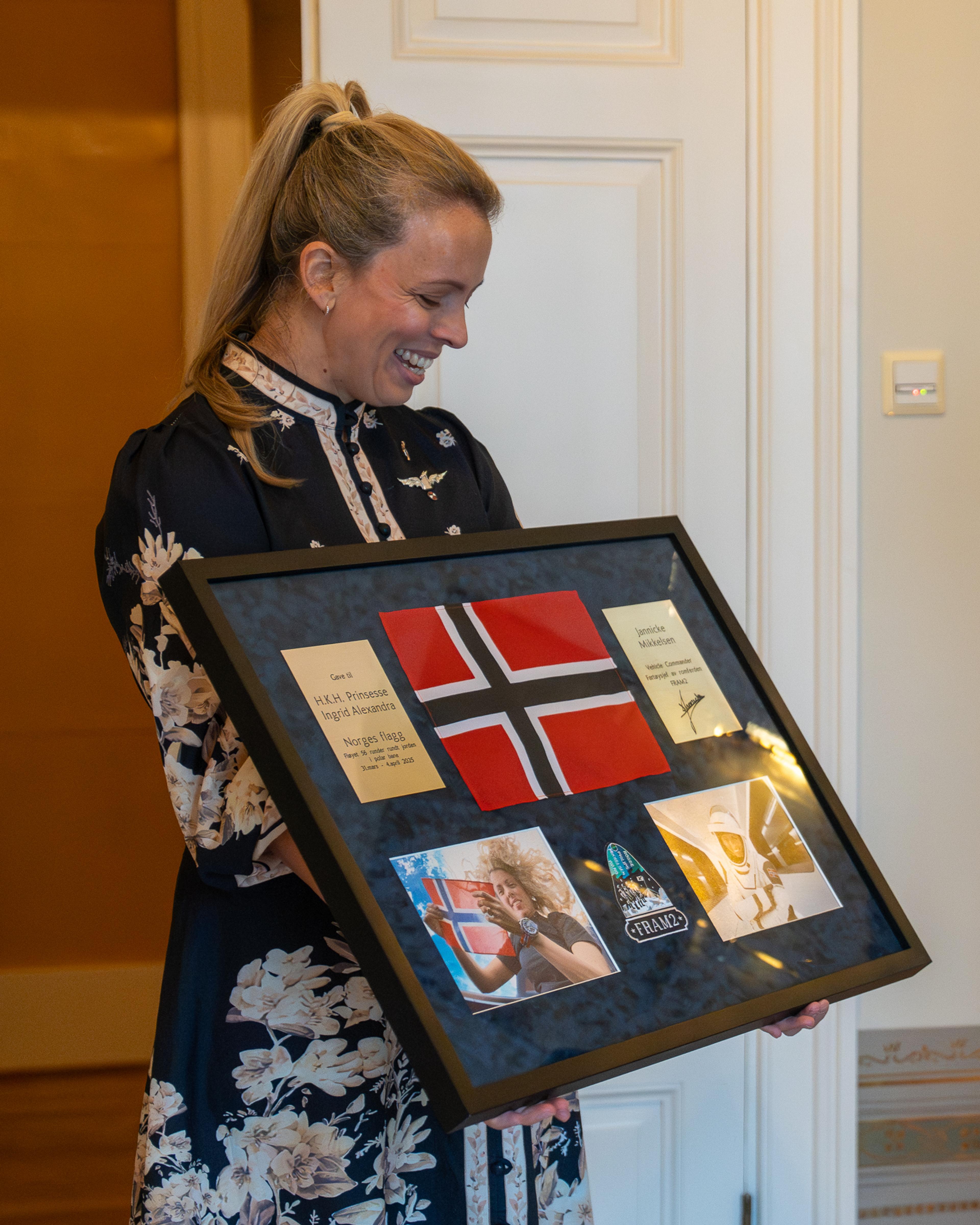 Astronaut Jannicke Mikkelsen holder et innrammet norsk flagg.