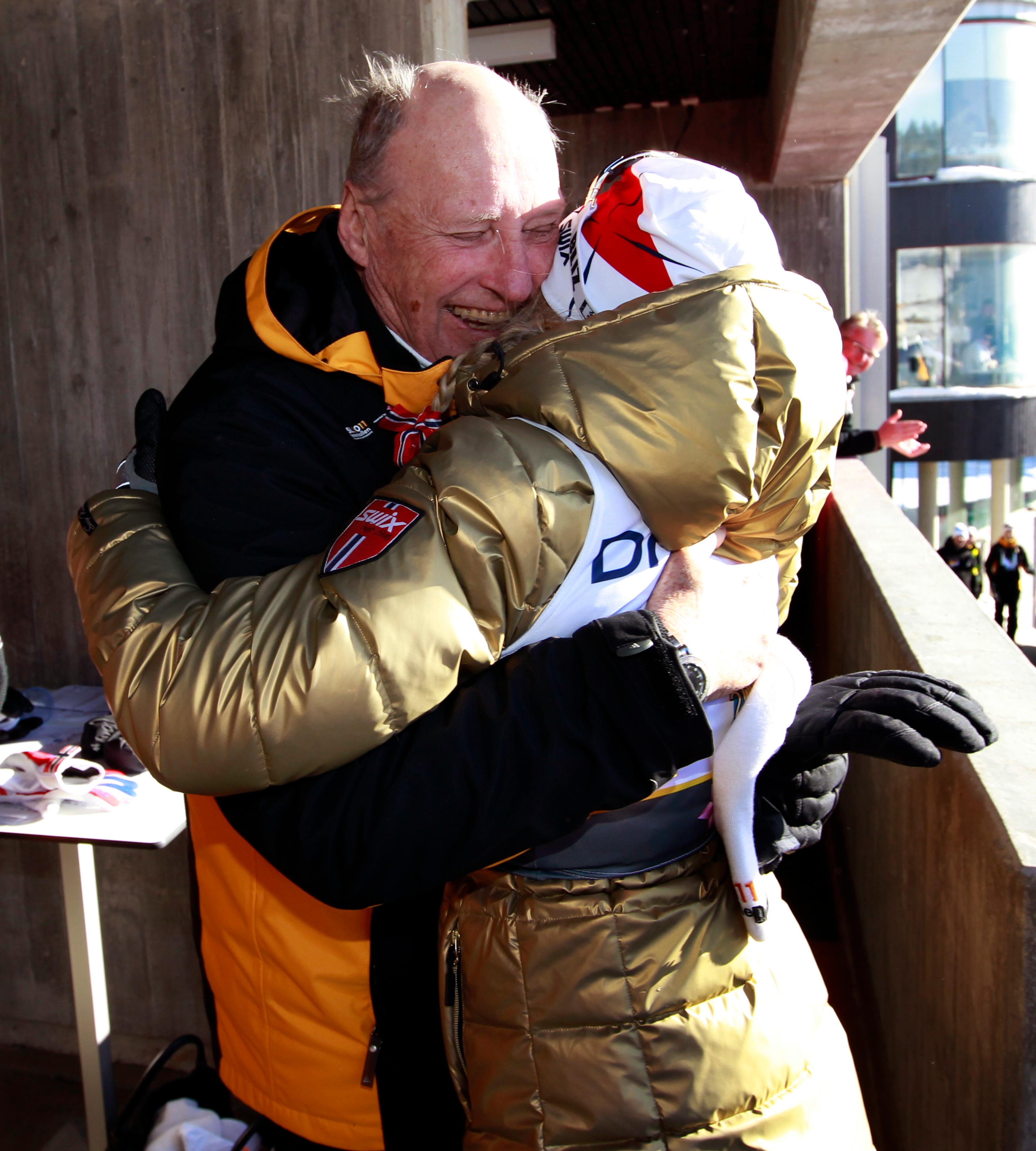 Johaug i gulljakke får en bamseklem av Kong Harald.