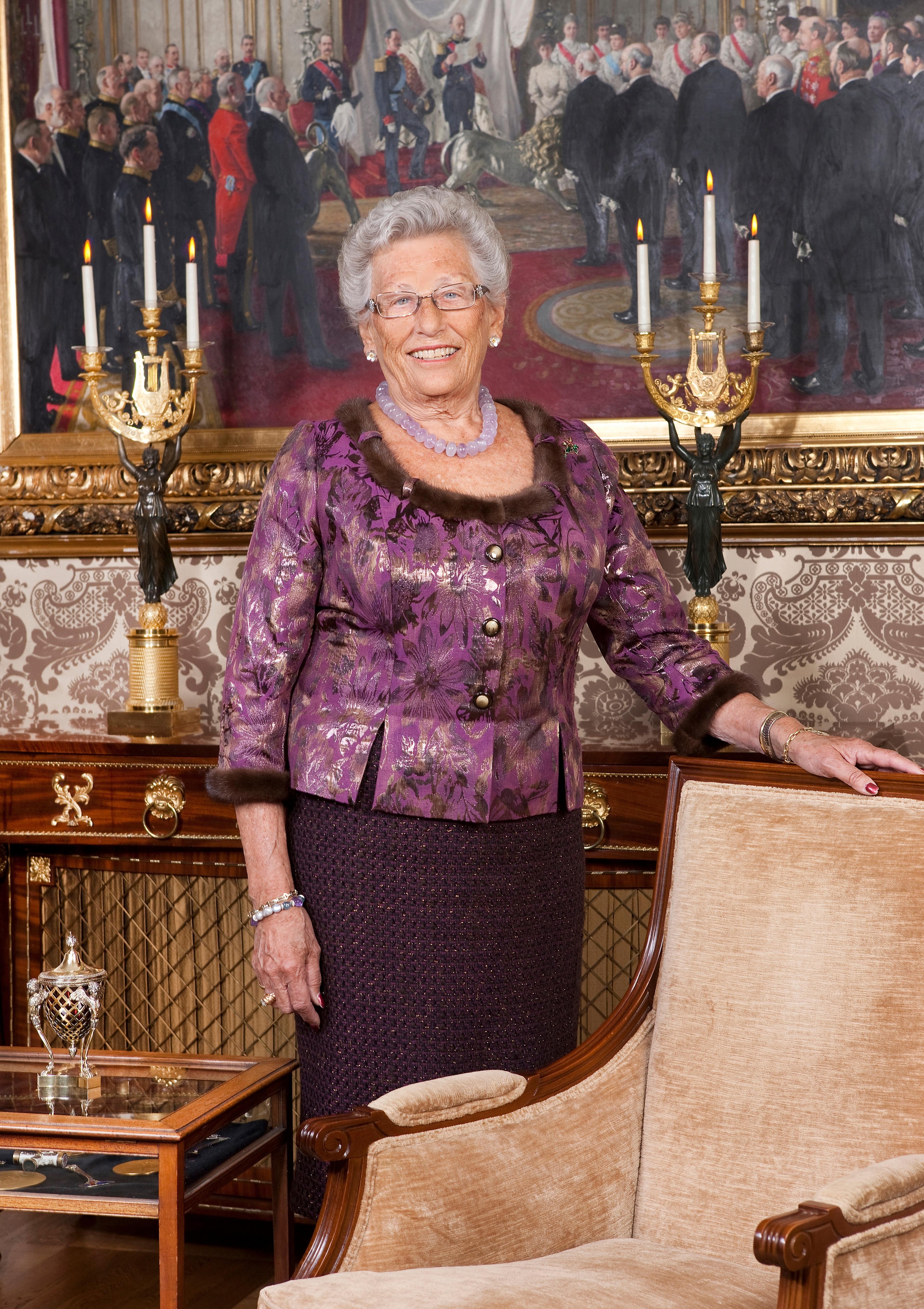 Prinsessen i helfigur, står med hånden på en stolrygg foran et maleri.