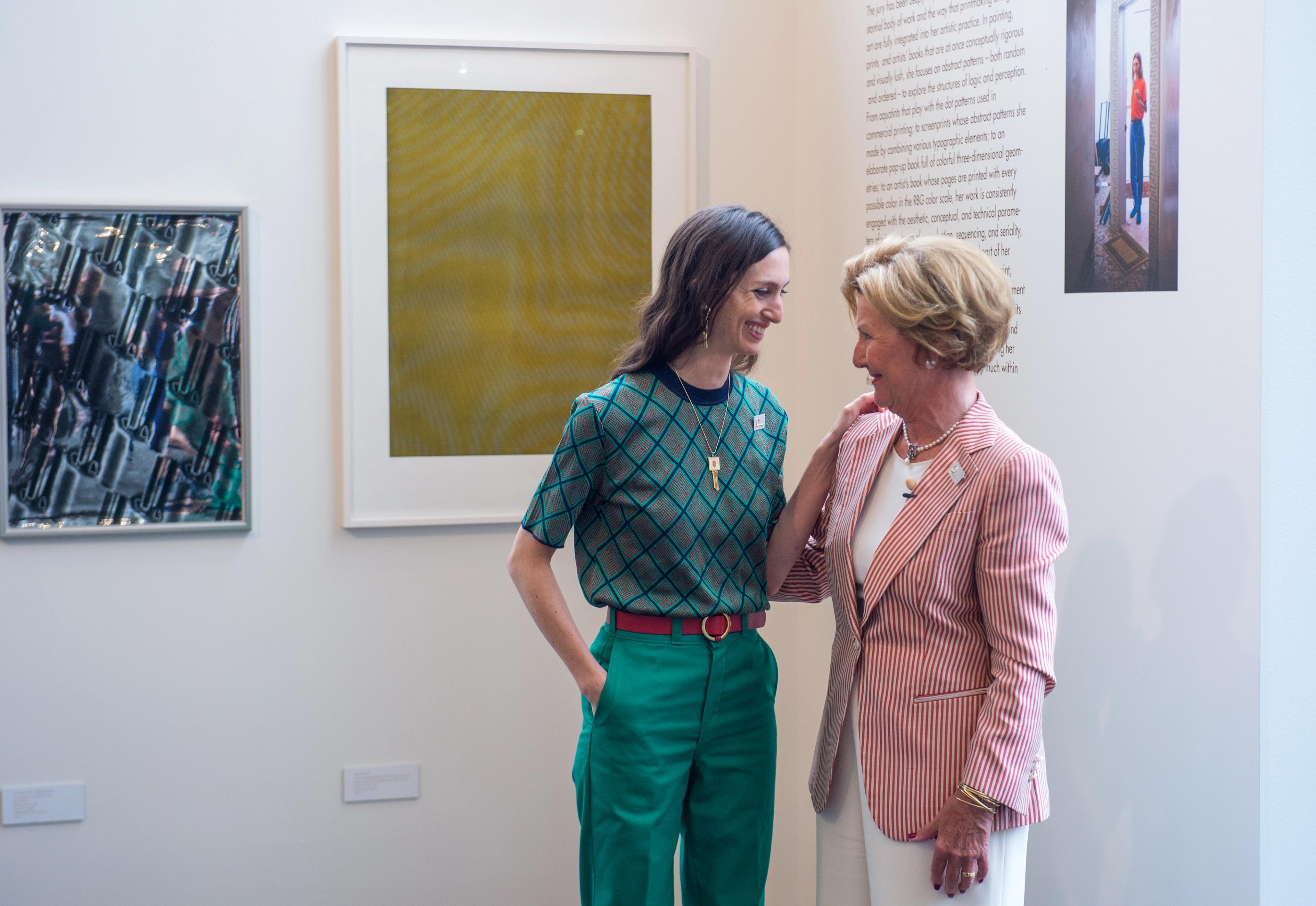 Dronning Sonja og Tauba Auerbach står foran en vegg med grafiske verk.