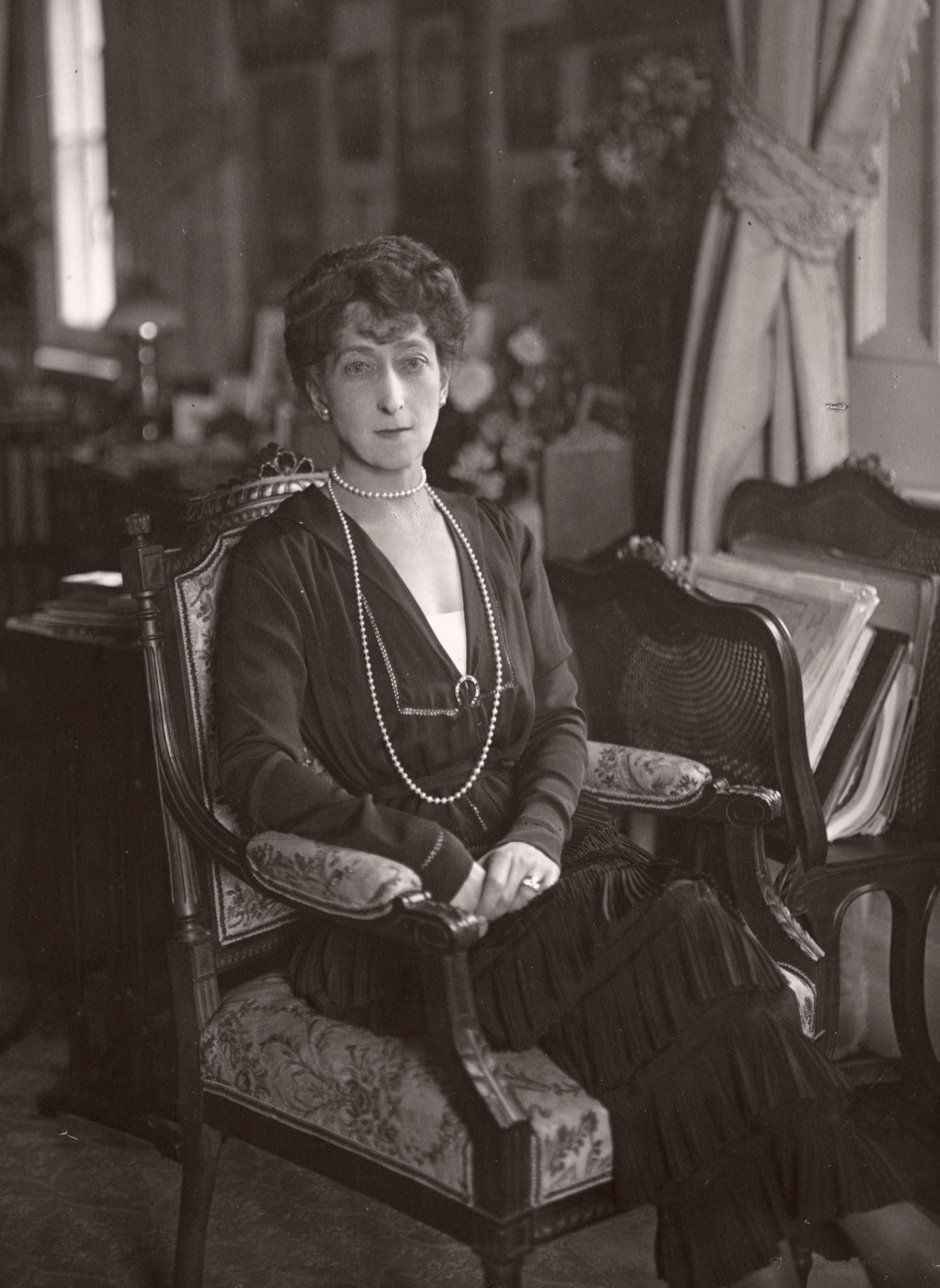 Dronning Maud i en stol i stuen.