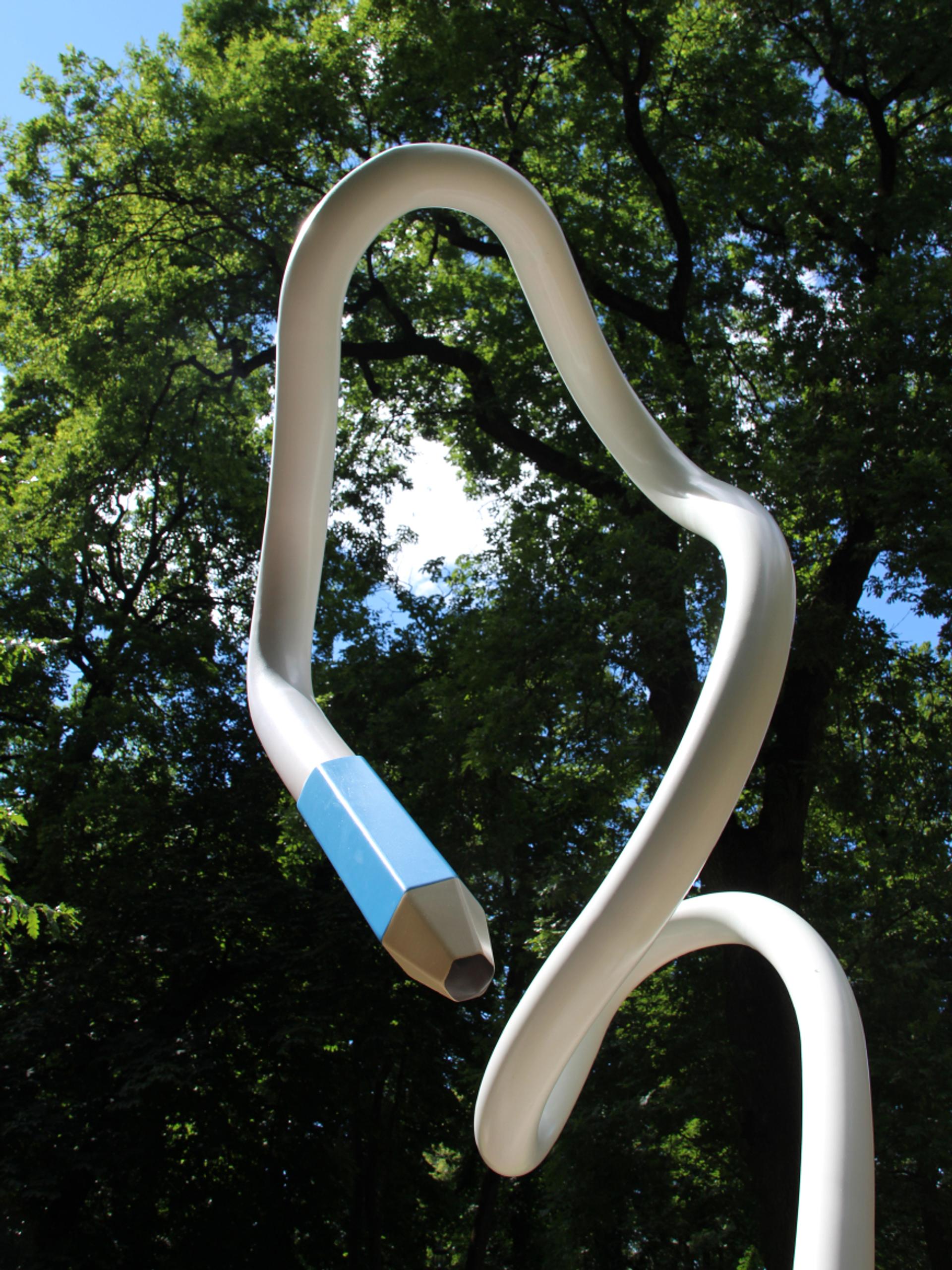 En hvit blyant kommer opp av bakken og bukter seg høyt opp i luften. Den svinger ned igjen, slik at tuppen - en blå blyantspiss - er omtrent i høyde med den som ser.