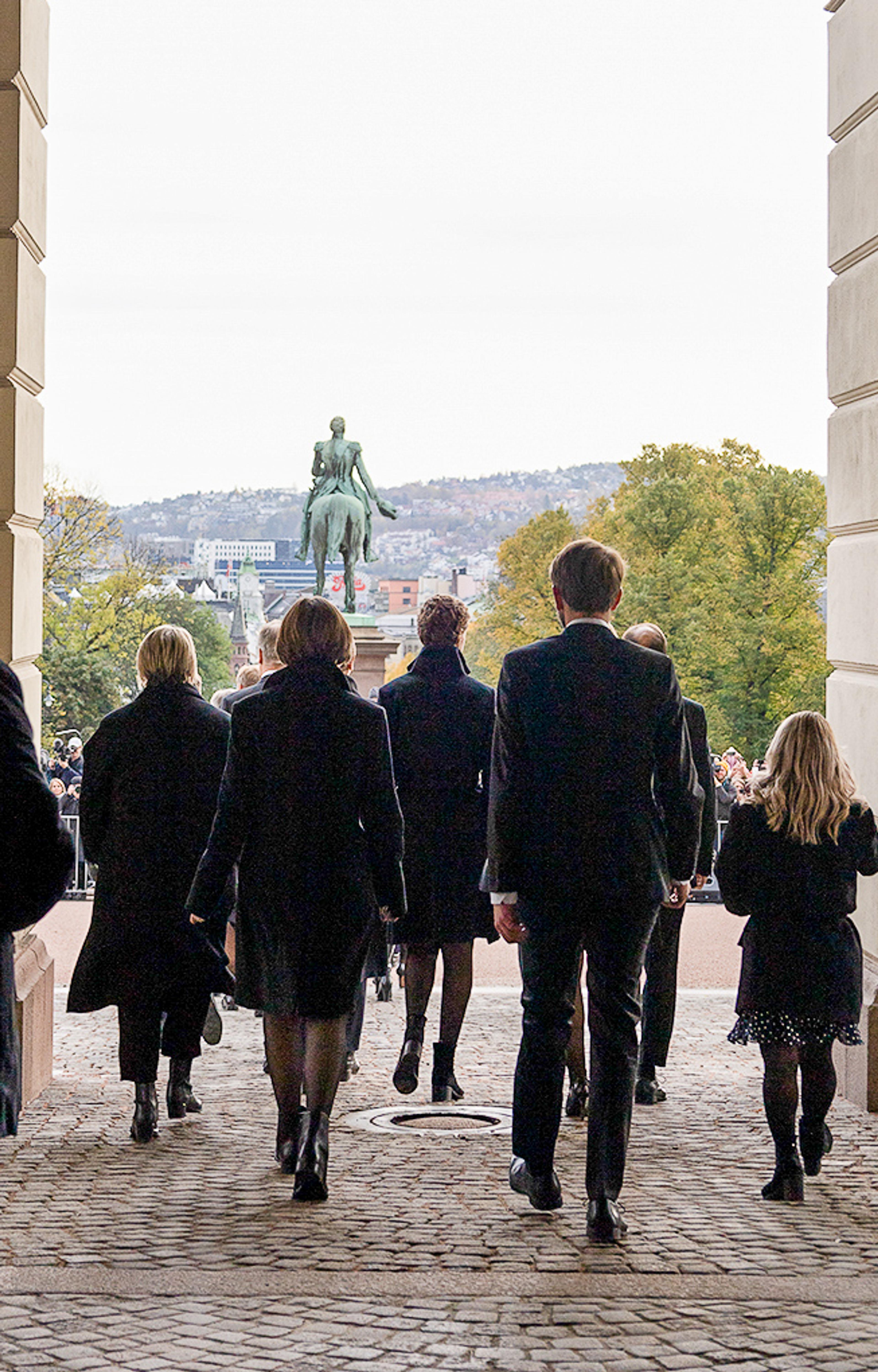 Vi ser regjeringen bakfra idet de passerer ut gjennom Slottets hovedport og ut på Slottsplassen.