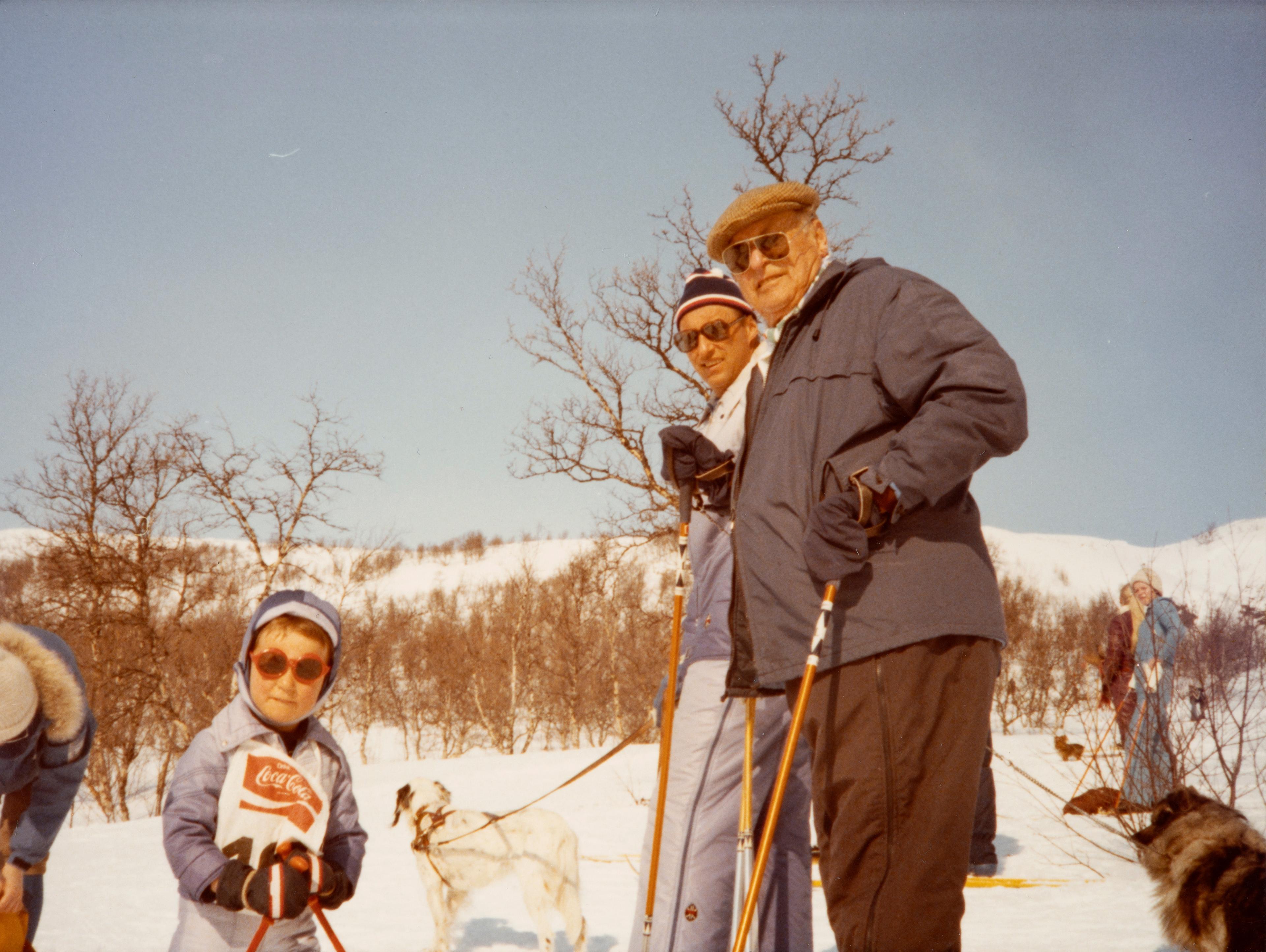 Alle står i skiutstyr. Familiens hund er med.