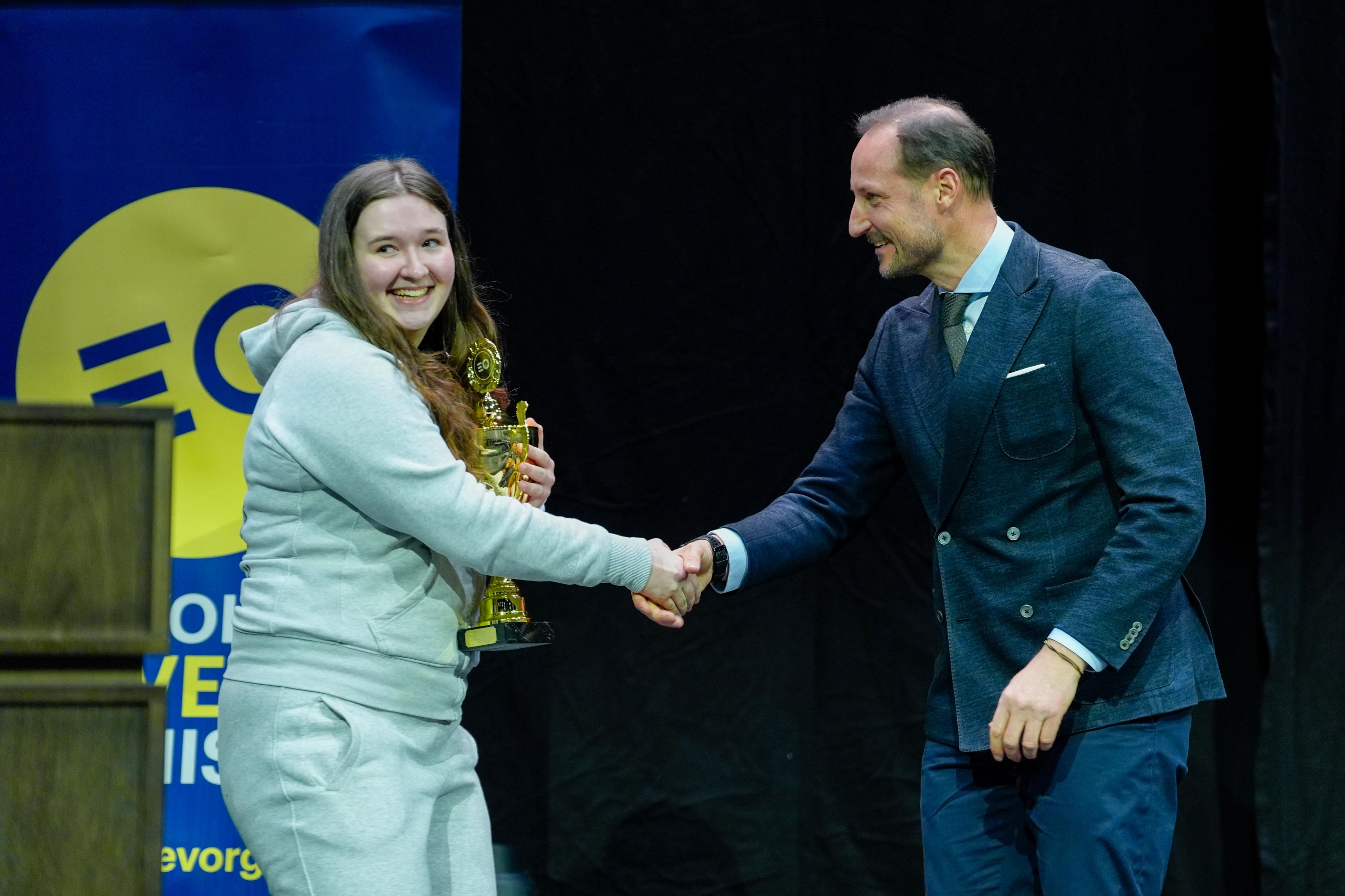 Kronprins Haakon tar ei jente i handa. Ho held pokalen.