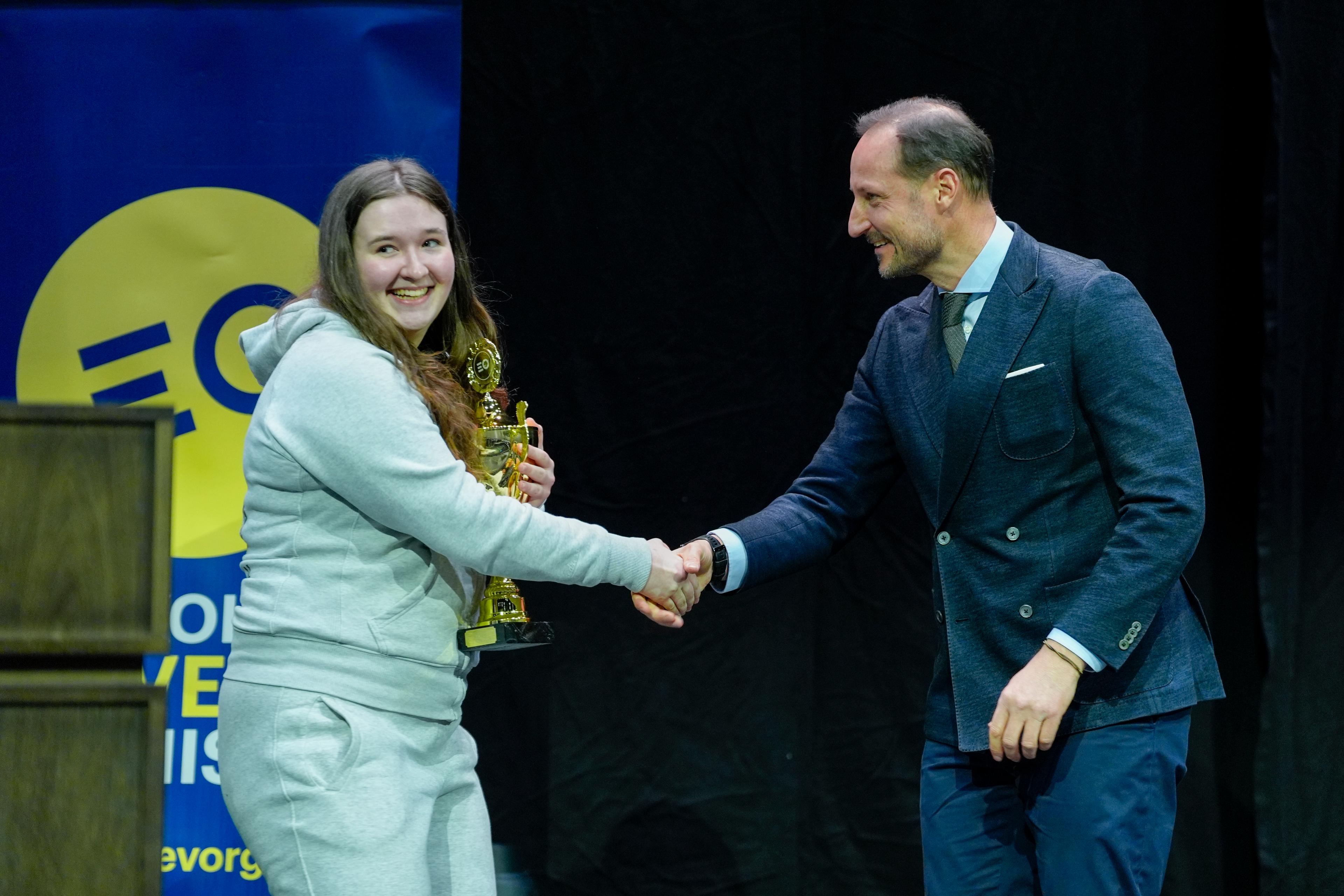 Kronprins Haakon tar ei jente i handa. Ho held pokalen.