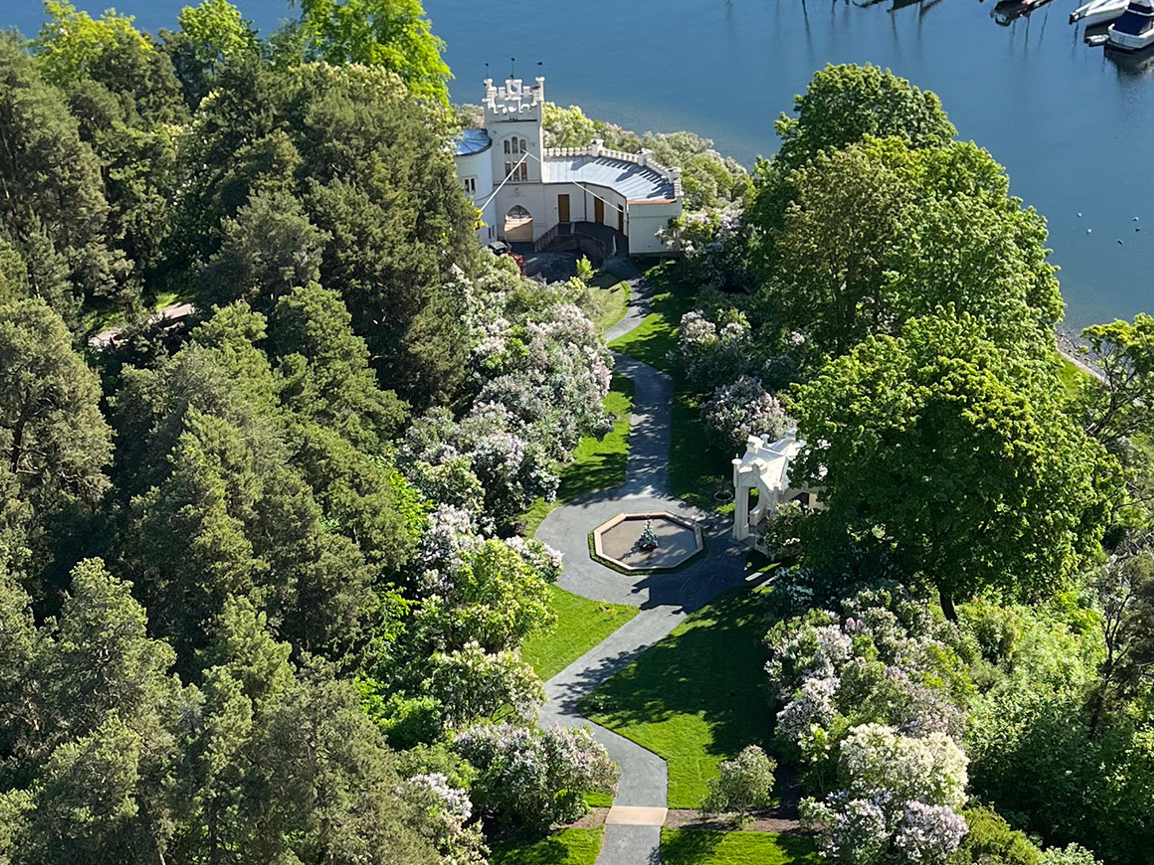 Parken er sett ovenfra. En gangvei slynger seg gjennom anlegget mellom blomstrende trær og busker, ned mot sjøen.