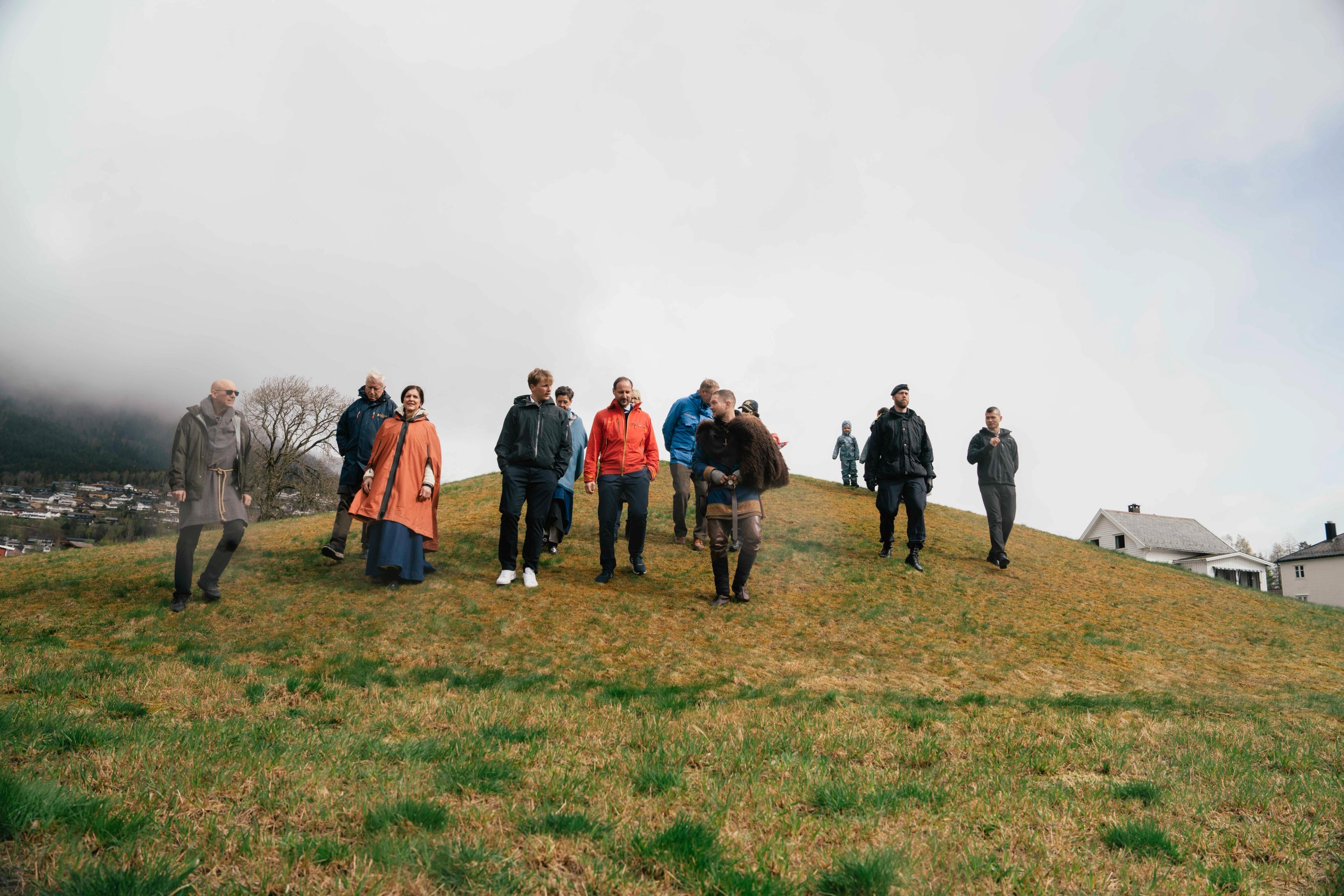 Kronprins Haakon og Prins Sverre Magnus går nedover gravhaugen der Myklebustskipet ble funnet sammen med et større følge.