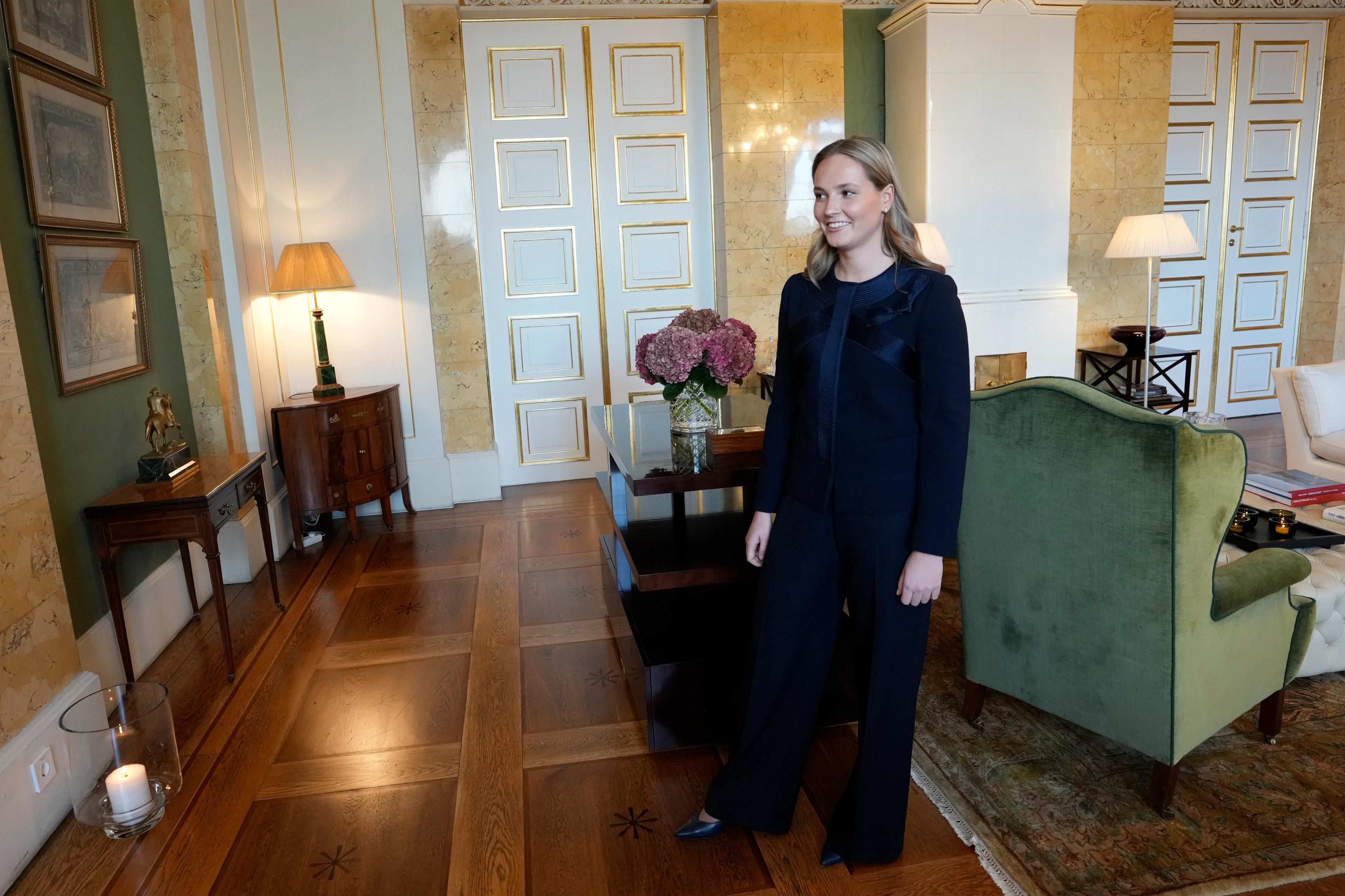 Kronprinsessen står smilende i værelset, som preges av hvitt og grønt.