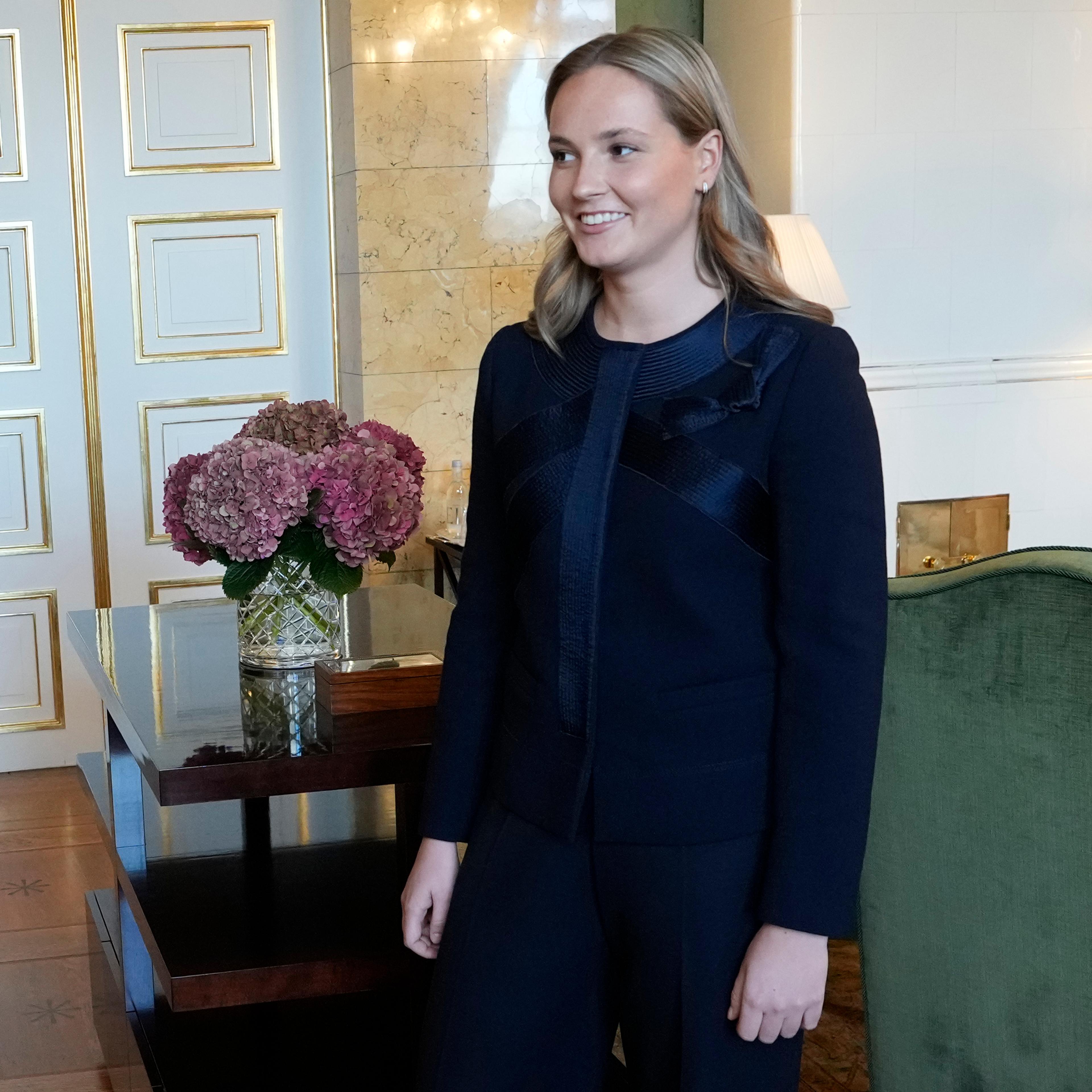 Kronprinsessen står smilende i værelset, som preges av hvitt og grønt.