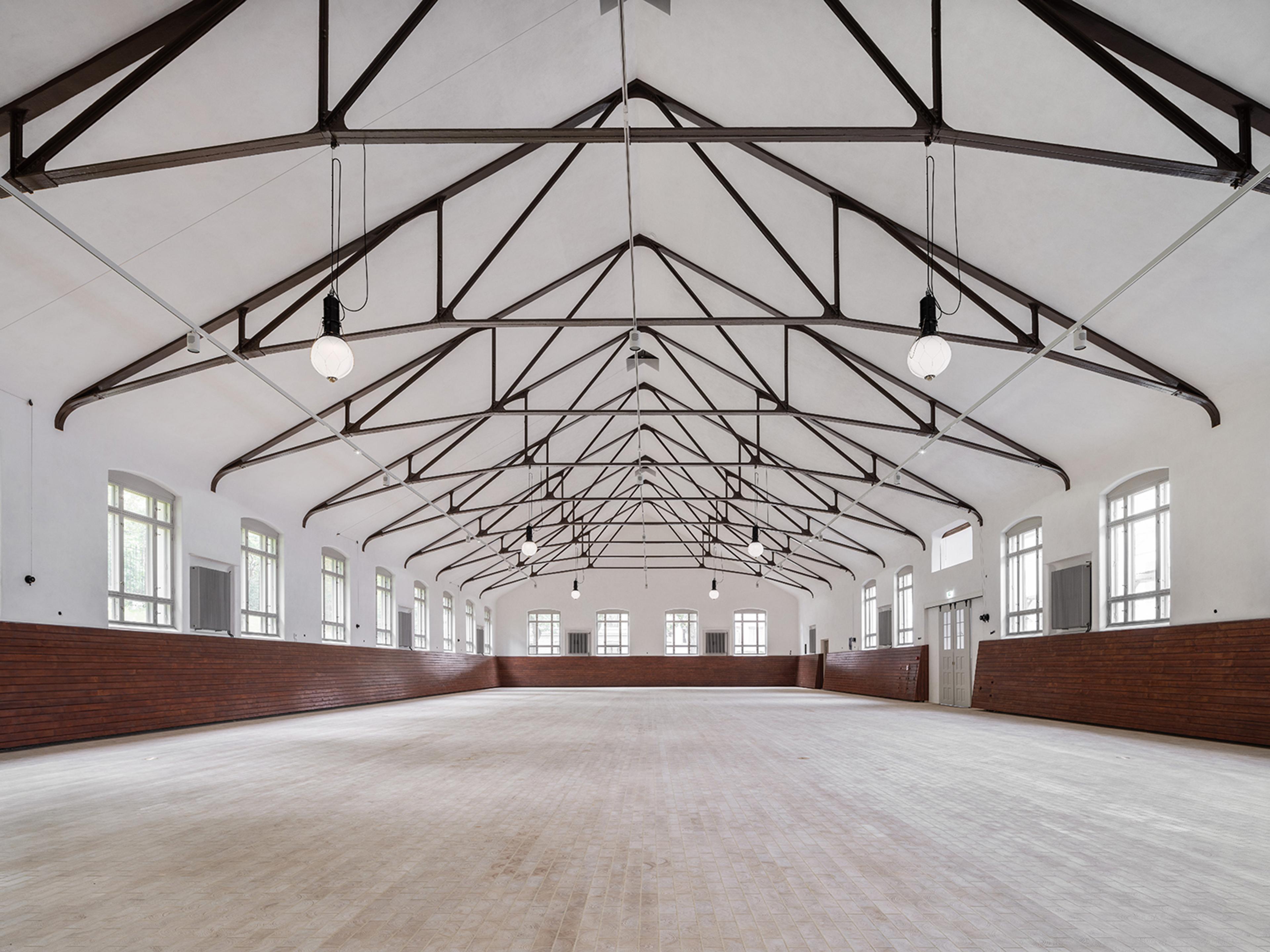 Det er et stort, åpent rom, hvitkalket, med lyst tregulv og med mørke trebjelker i taket. 