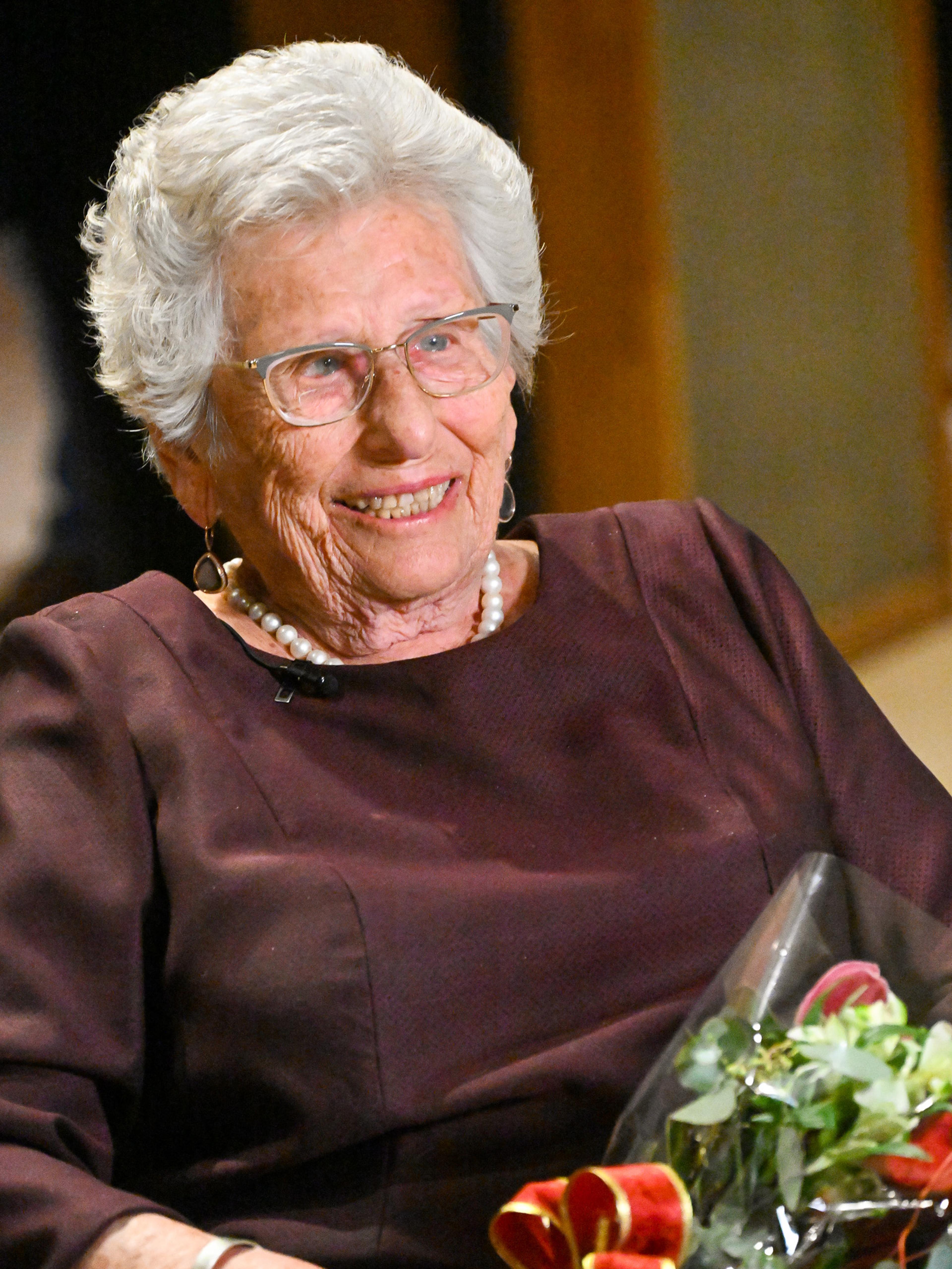 Prinsessen på plass i salen, smilende med blomster i fanget.