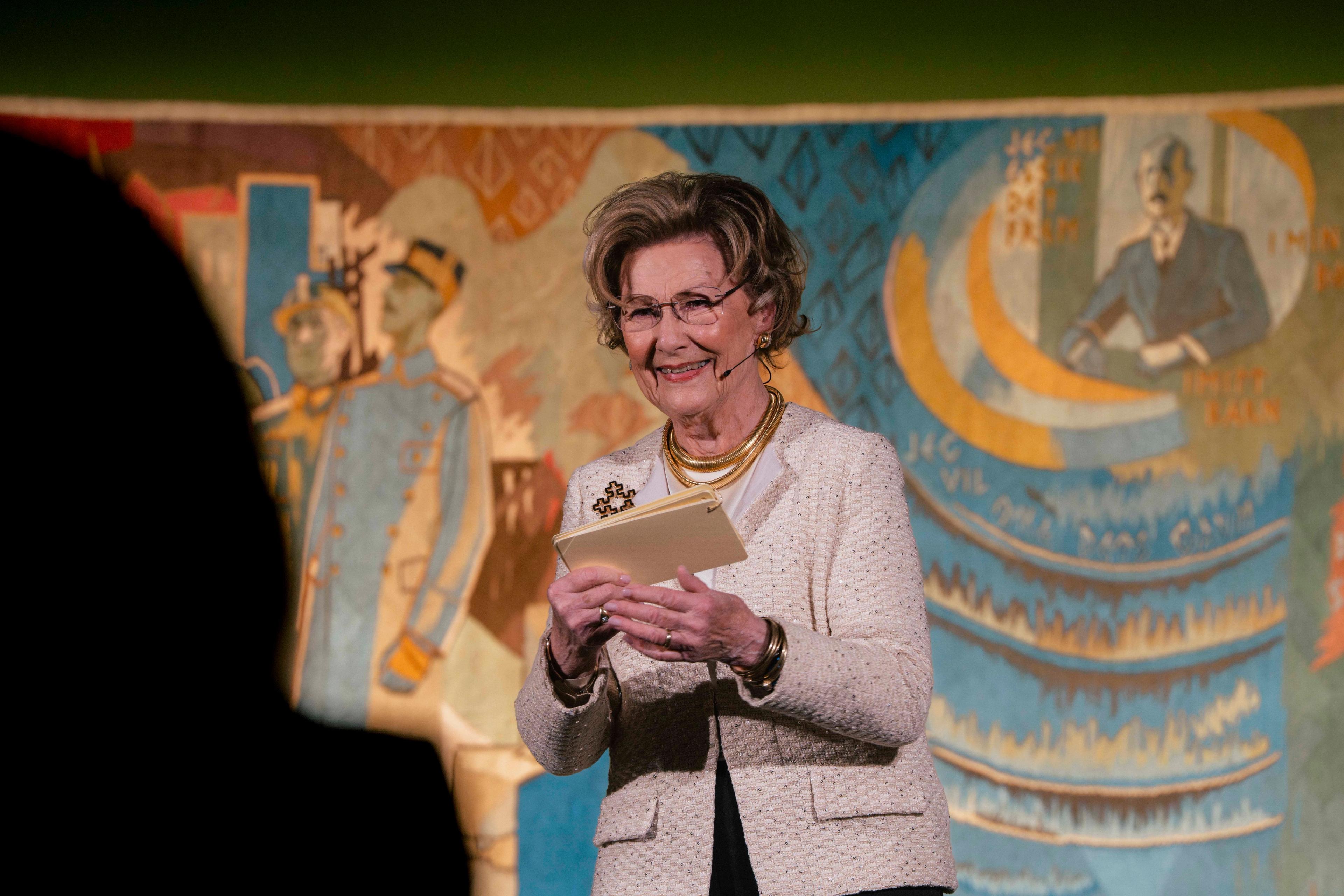 Dronning Sonja på scenen med Kongeteppet i bakgrunnen.