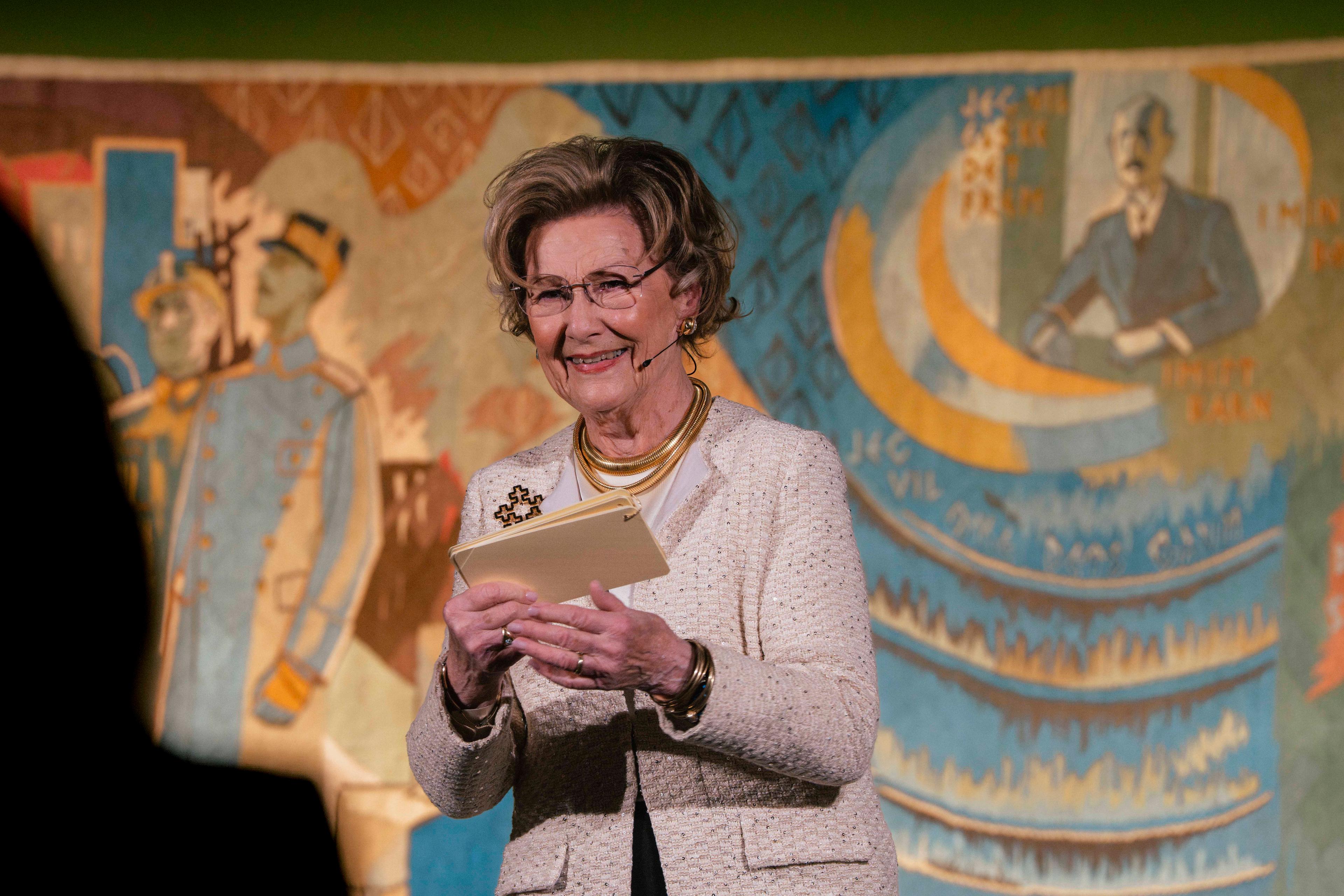 Dronning Sonja på scenen med Kongeteppet i bakgrunnen.